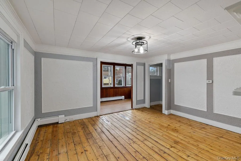 Empty room featuring light hardwood / wood-style floors, baseboard heating, and ornamental molding Empty room featuring light hardwood / wood-style floors, baseboard heating, and ornamental molding