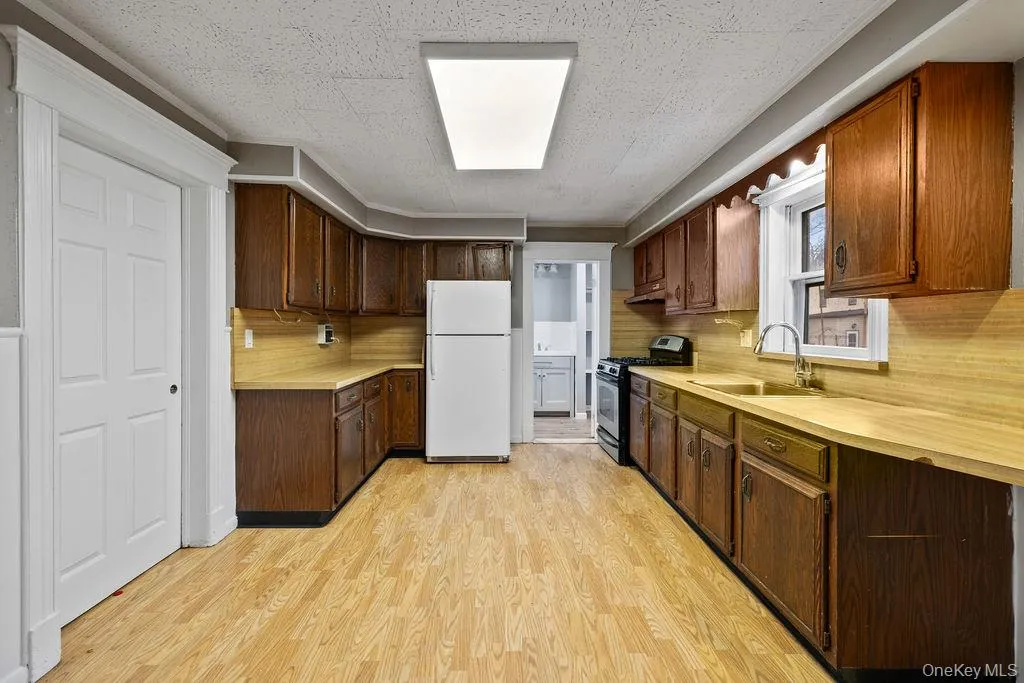 Kitchen featuring decorative backsplash, white fridge, sink, and gas range Kitchen featuring decorative backsplash, white fridge, sink, and gas range