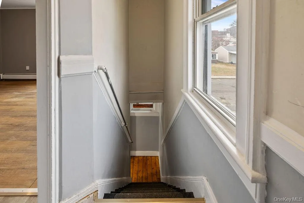 Stairs featuring wood-type flooring and a baseboard radiator Stairs featuring wood-type flooring and a baseboard radiator
