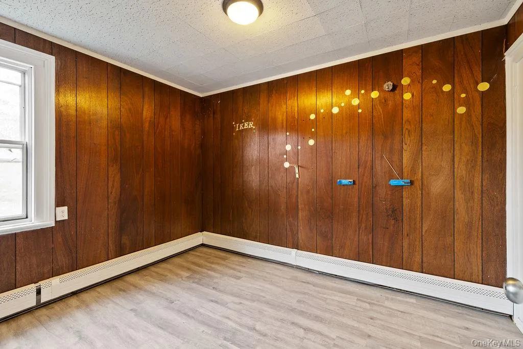 Spare room featuring wood walls and light hardwood / wood-style flooring Spare room featuring wood walls and light hardwood / wood-style flooring