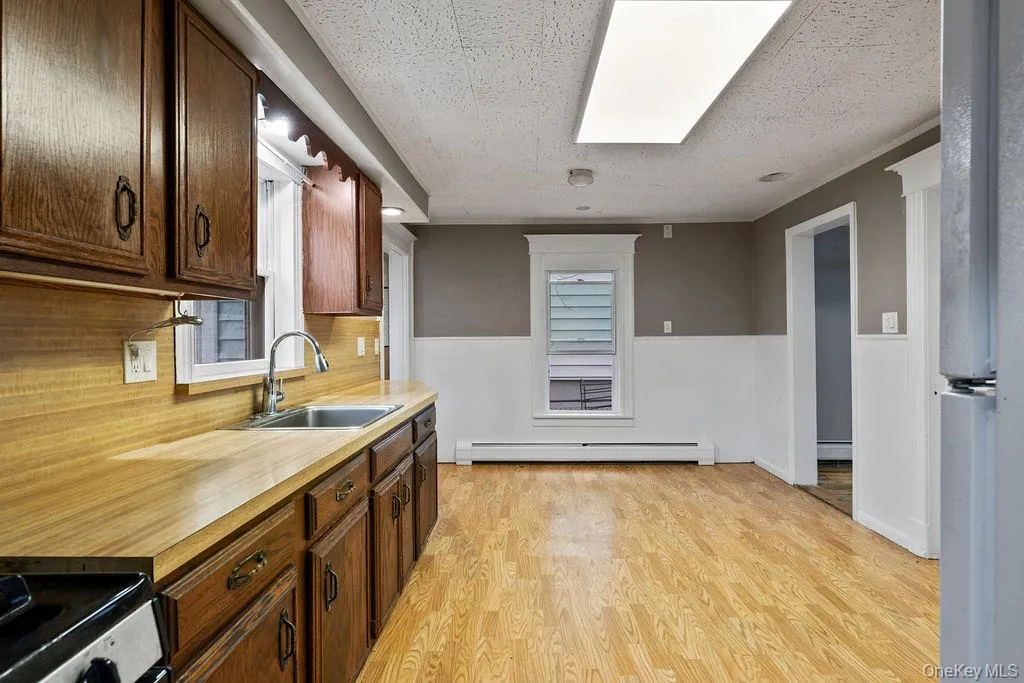 Kitchen with backsplash, sink, a textured ceiling, and a baseboard heating unit Kitchen with backsplash, sink, a textured ceiling, and a baseboard heating unit