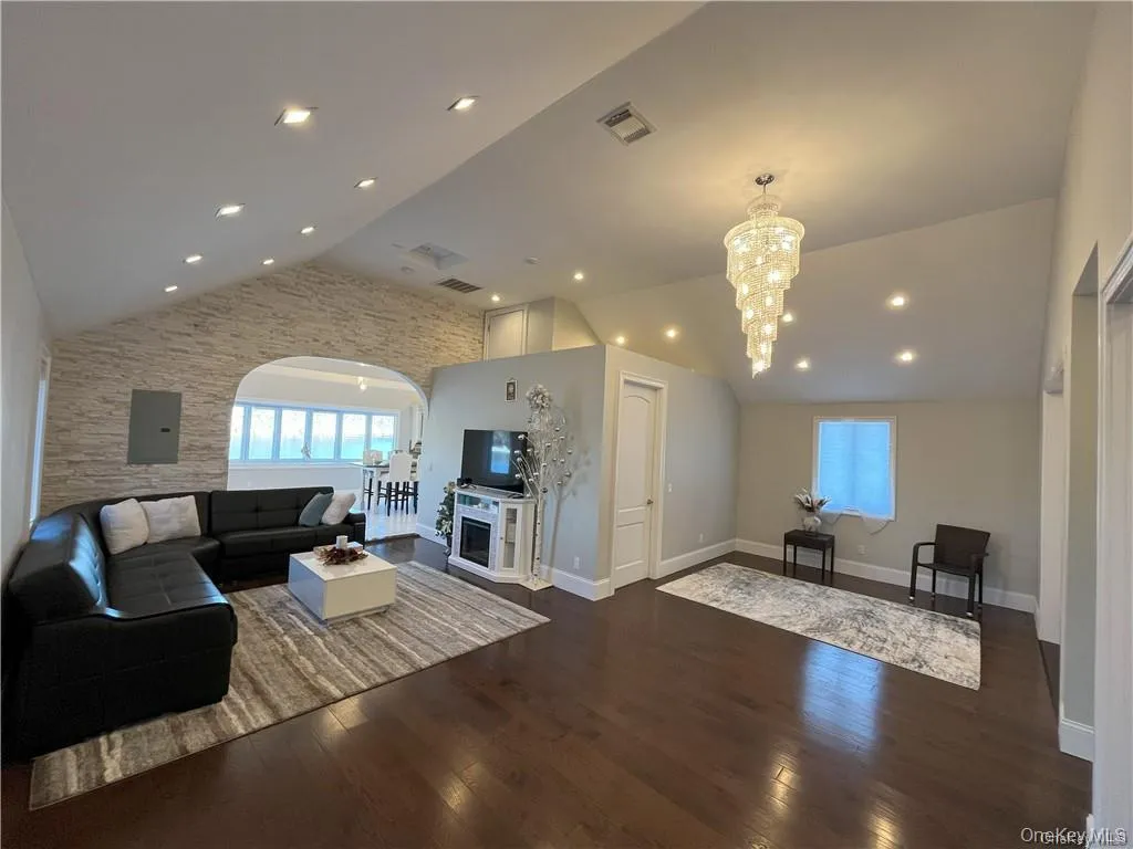 Living room featuring a notable chandelier, dark wood flooring, and high ceilings Living room featuring a notable chandelier, dark wood flooring, and high ceilings