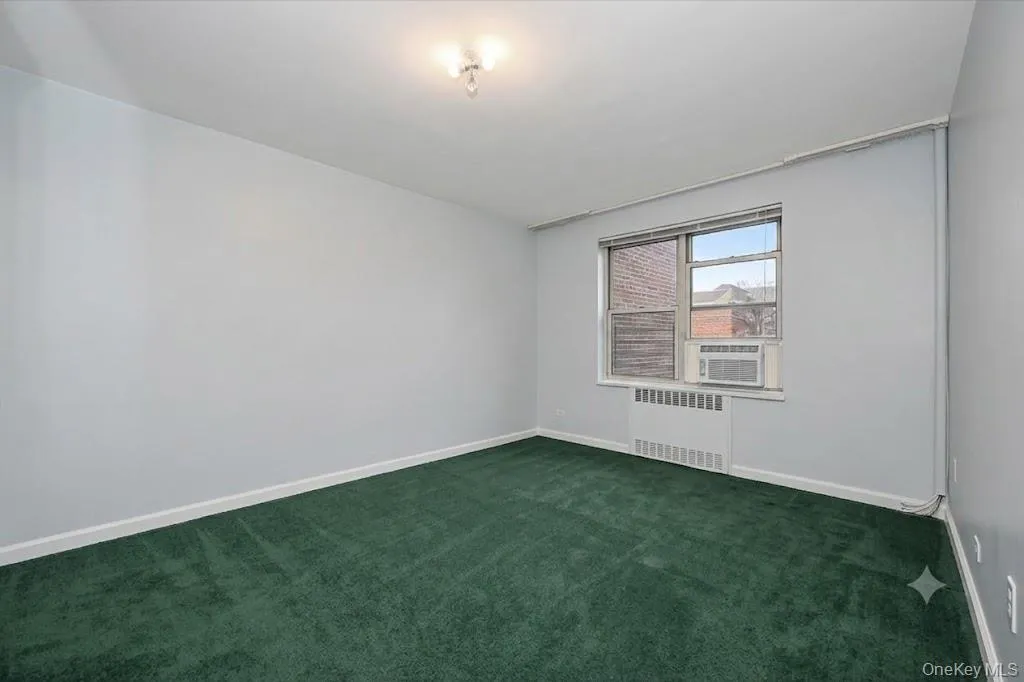 Room with green carpet flooring, light grey walls, white baseboards, and a window with blinds Room with green carpet flooring, light grey walls, white baseboards, and a window with blinds