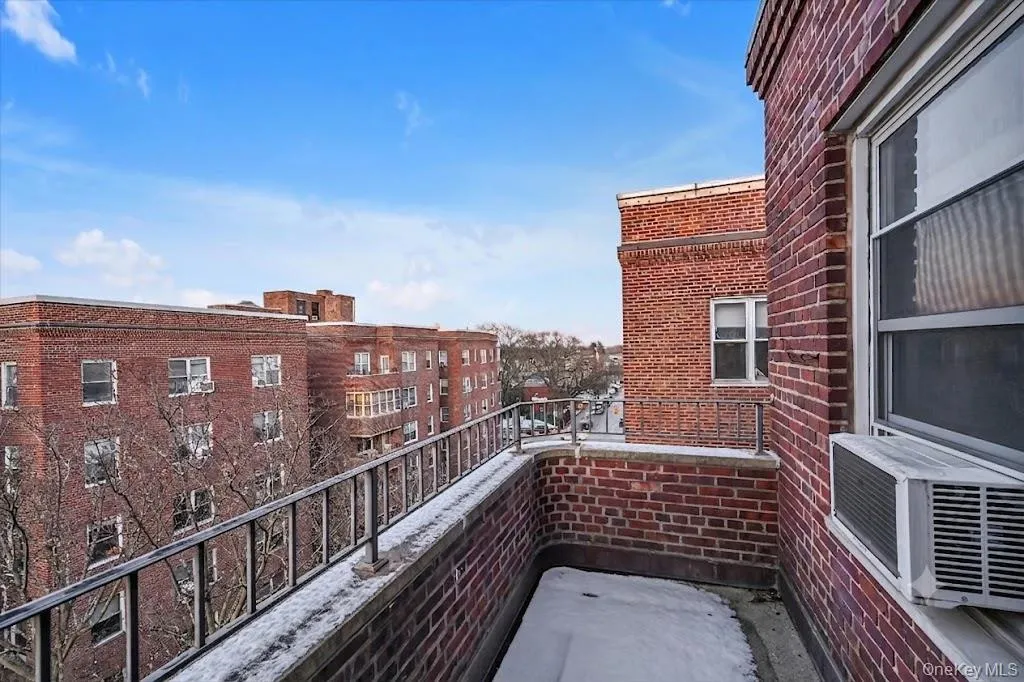 Balcony featuring brick construction, a metal railing, and a window unit air conditioner Balcony featuring brick construction, a metal railing, and a window unit air conditioner
