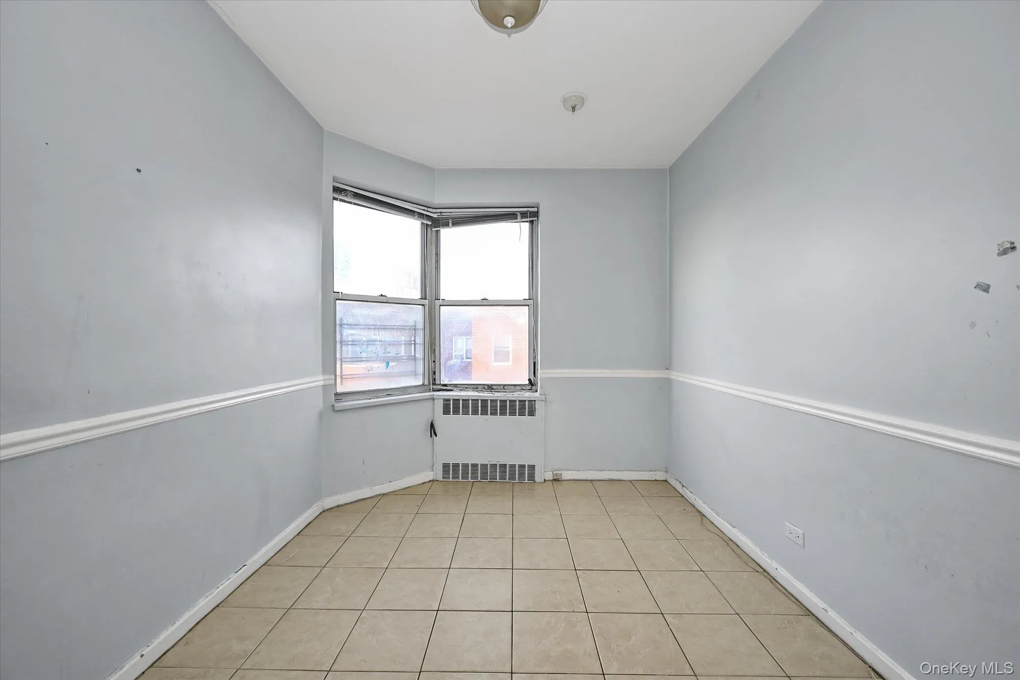 Bay window with multiple panes, tiled flooring, wall-mounted heating unit, and white chair rail molding Bay window with multiple panes, tiled flooring, wall-mounted heating unit, and white chair rail molding