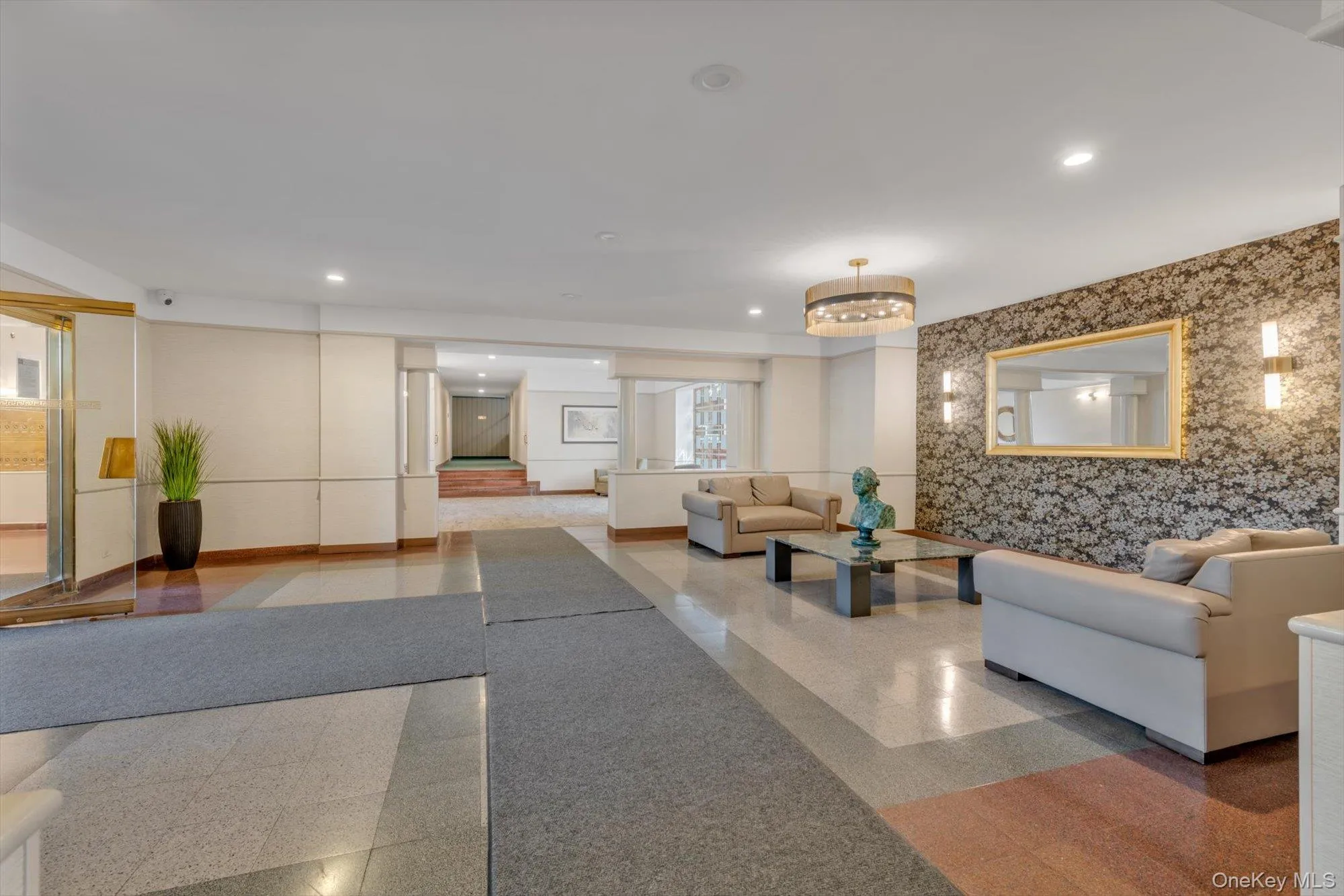 Lobby area featuring patterned accent wall, recessed lighting, and a prominent chandelier Lobby area featuring patterned accent wall, recessed lighting, and a prominent chandelier