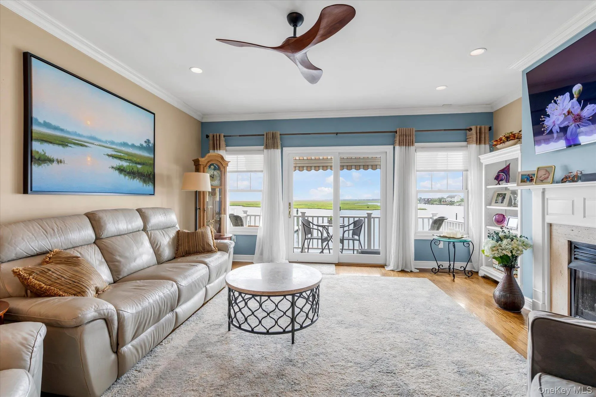 Living area featuring wood-finish flooring, crown molding, and recessed lighting gas fire place- sliders to a trex balcony Living area featuring wood-finish flooring, crown molding, and recessed lighting gas fire place- sliders to a trex balcony