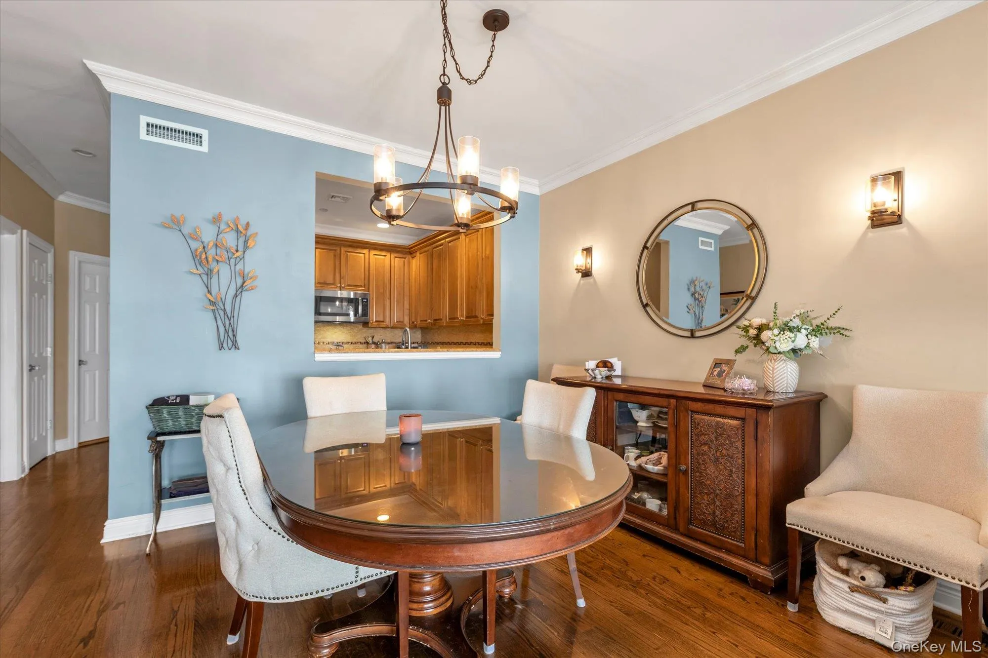 Dining area featuring wood-finish flooring, crown molding, and a kitchen pass-through Dining area featuring wood-finish flooring, crown molding, and a kitchen pass-through