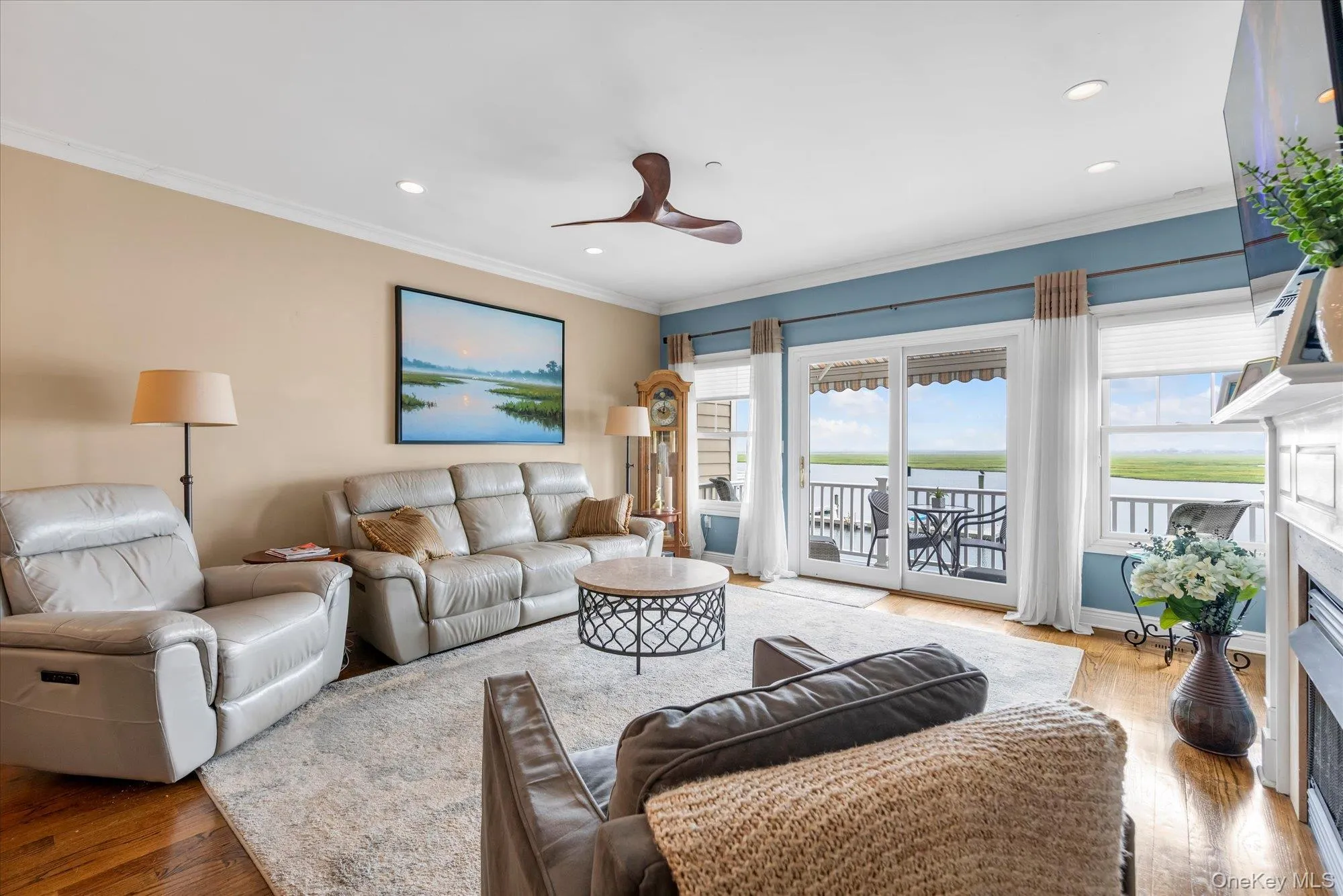 Open-concept living area with wood-finish flooring and crown molding-sliders to trex balcony Open-concept living area with wood-finish flooring and crown molding-sliders to trex balcony