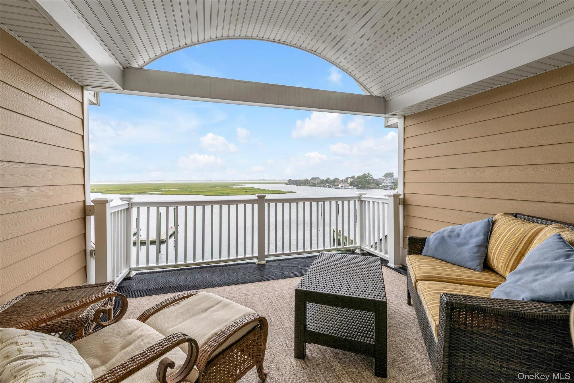 Covered outdoor balcony featuring a water frontage, white railing, and paneled siding-private sanctuary off your primary bedroom Covered outdoor balcony featuring a water frontage, white railing, and paneled siding-private sanctuary off your primary bedroom