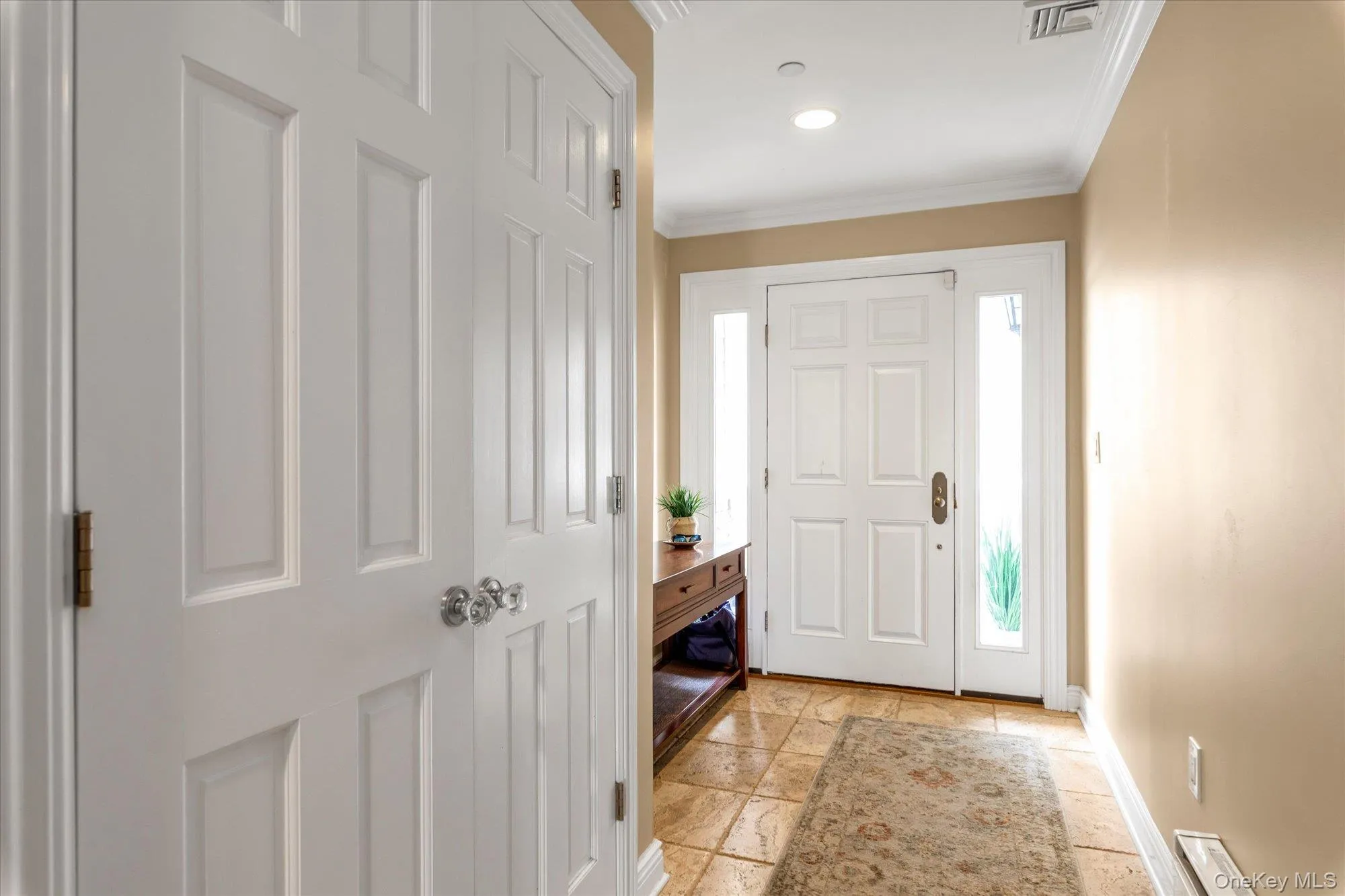 Foyer featuring a paneled entry door with sidelights, crown molding, recessed lighting, and tile flooring, Large coat closet Foyer featuring a paneled entry door with sidelights, crown molding, recessed lighting, and tile flooring, Large coat closet
