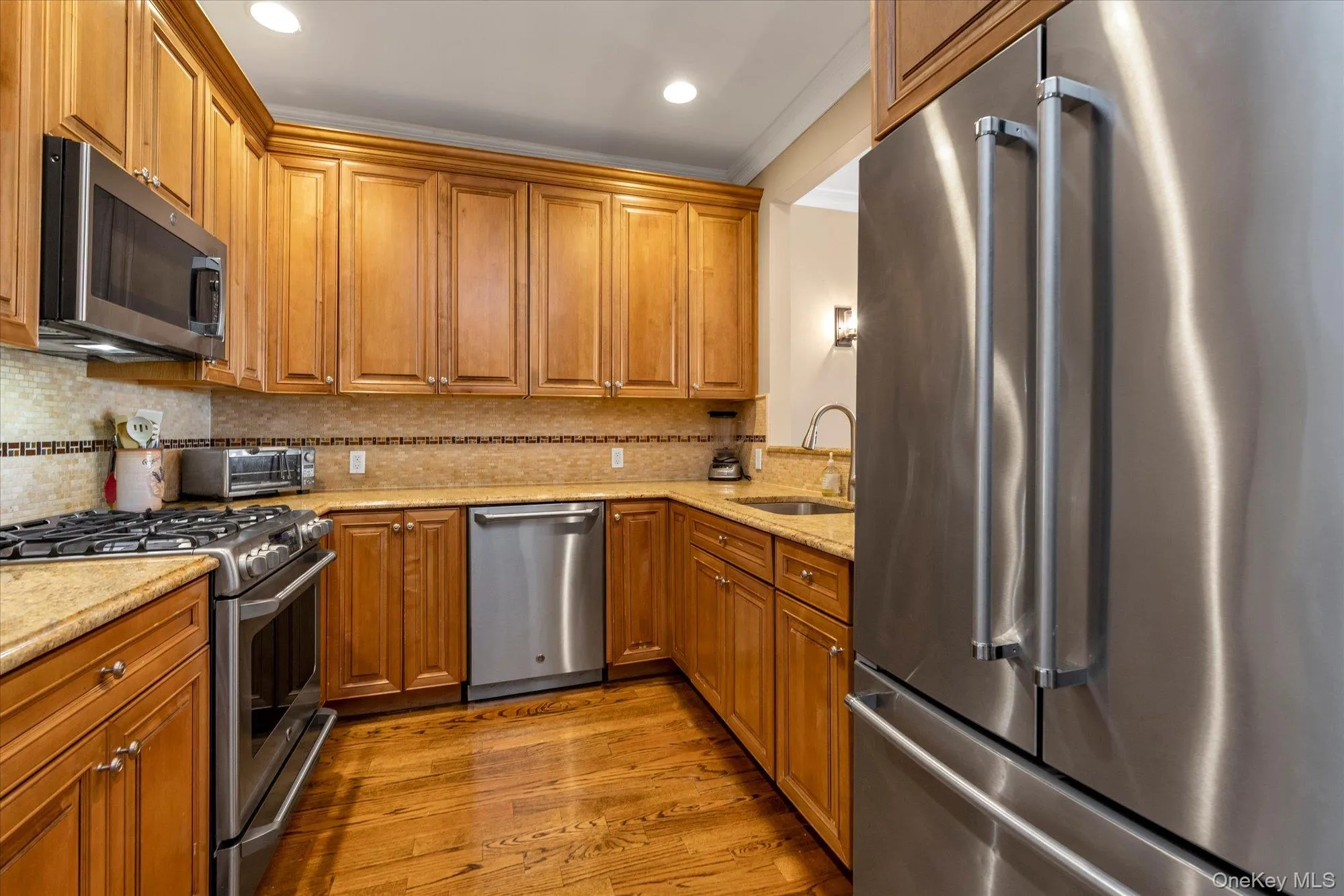 Kitchen featuring wood-finish cabinetry and stainless steel appliances, including a built-in microwave, gas range, dishwasher, and side-by-side refrigerator Kitchen featuring wood-finish cabinetry and stainless steel appliances, including a built-in microwave, gas range, dishwasher, and side-by-side refrigerator