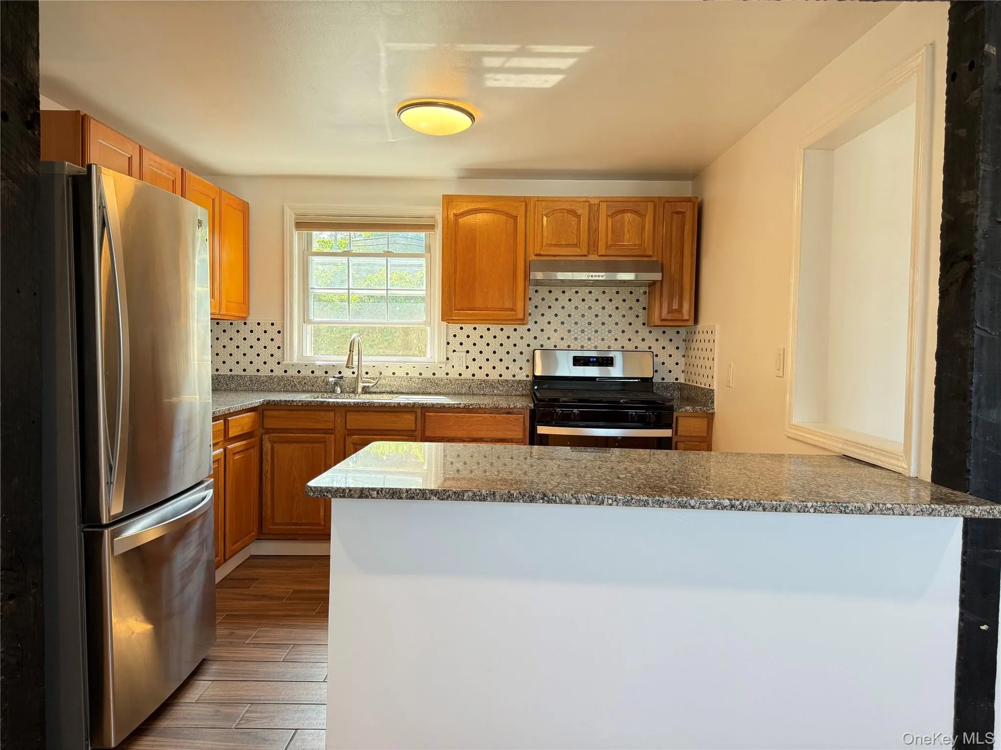 Bright and sunny open-concept kitchen with granite counter-tops, stainless steel appliances, and a large counter ideal for eat-in dining. Bright and sunny open-concept kitchen with granite counter-tops, stainless steel appliances, and a large counter ideal for eat-in dining.