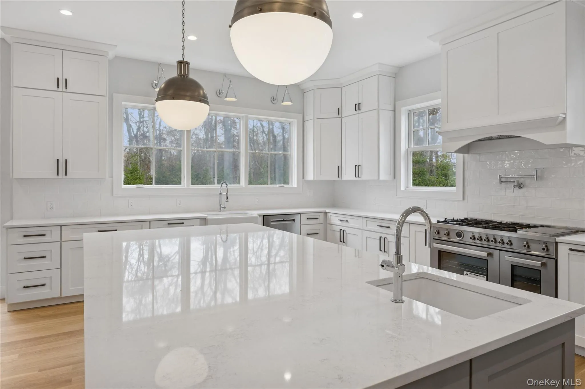 Kitchen with light wood-style flooring, appliances with stainless steel finishes, backsplash, light stone countertops, and recessed lighting Kitchen with light wood-style flooring, appliances with stainless steel finishes, backsplash, light stone countertops, and recessed lighting