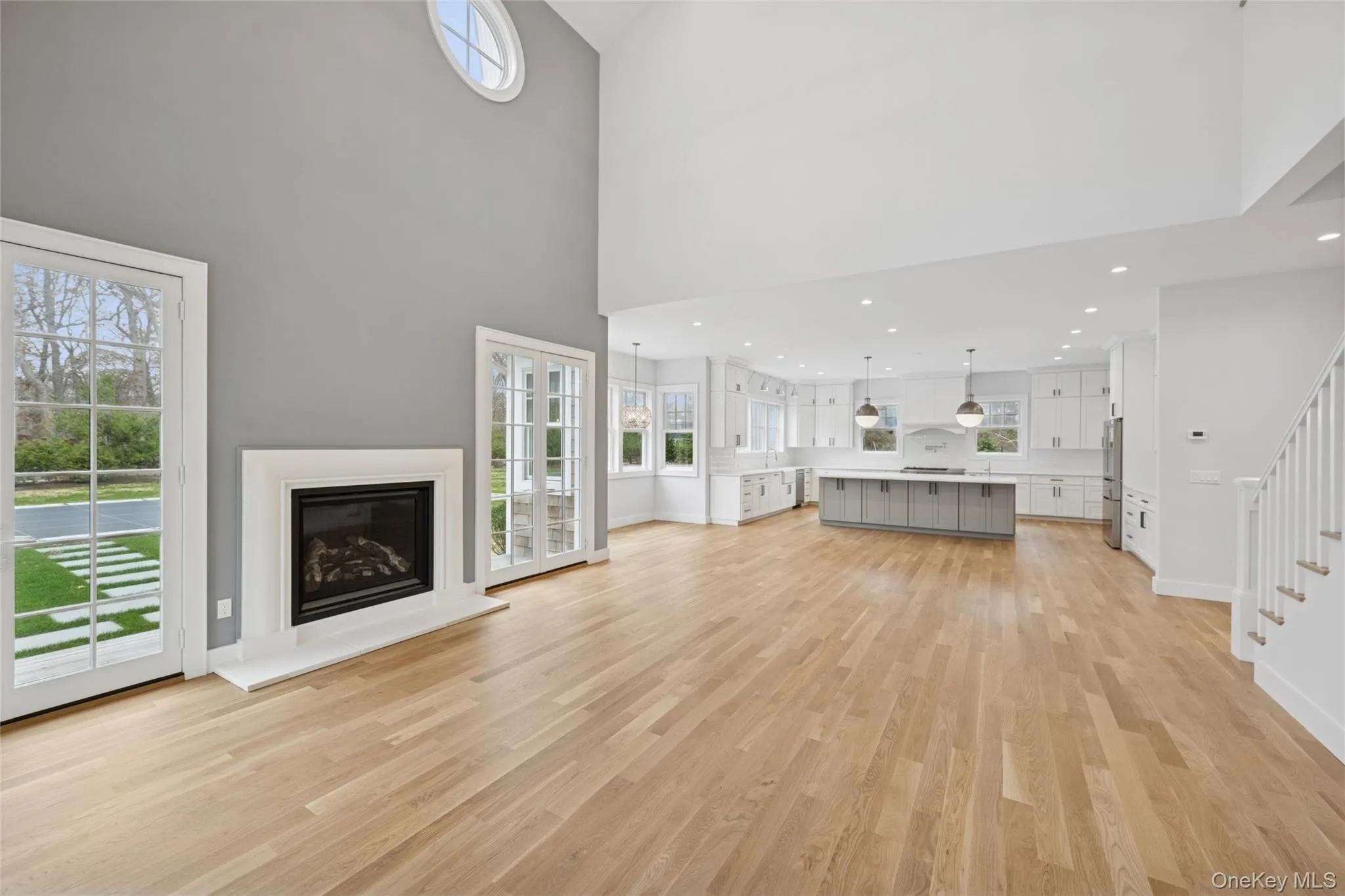 Living room with a glass covered fireplace, light wood finished floors, and a high ceiling Living room with a glass covered fireplace, light wood finished floors, and a high ceiling