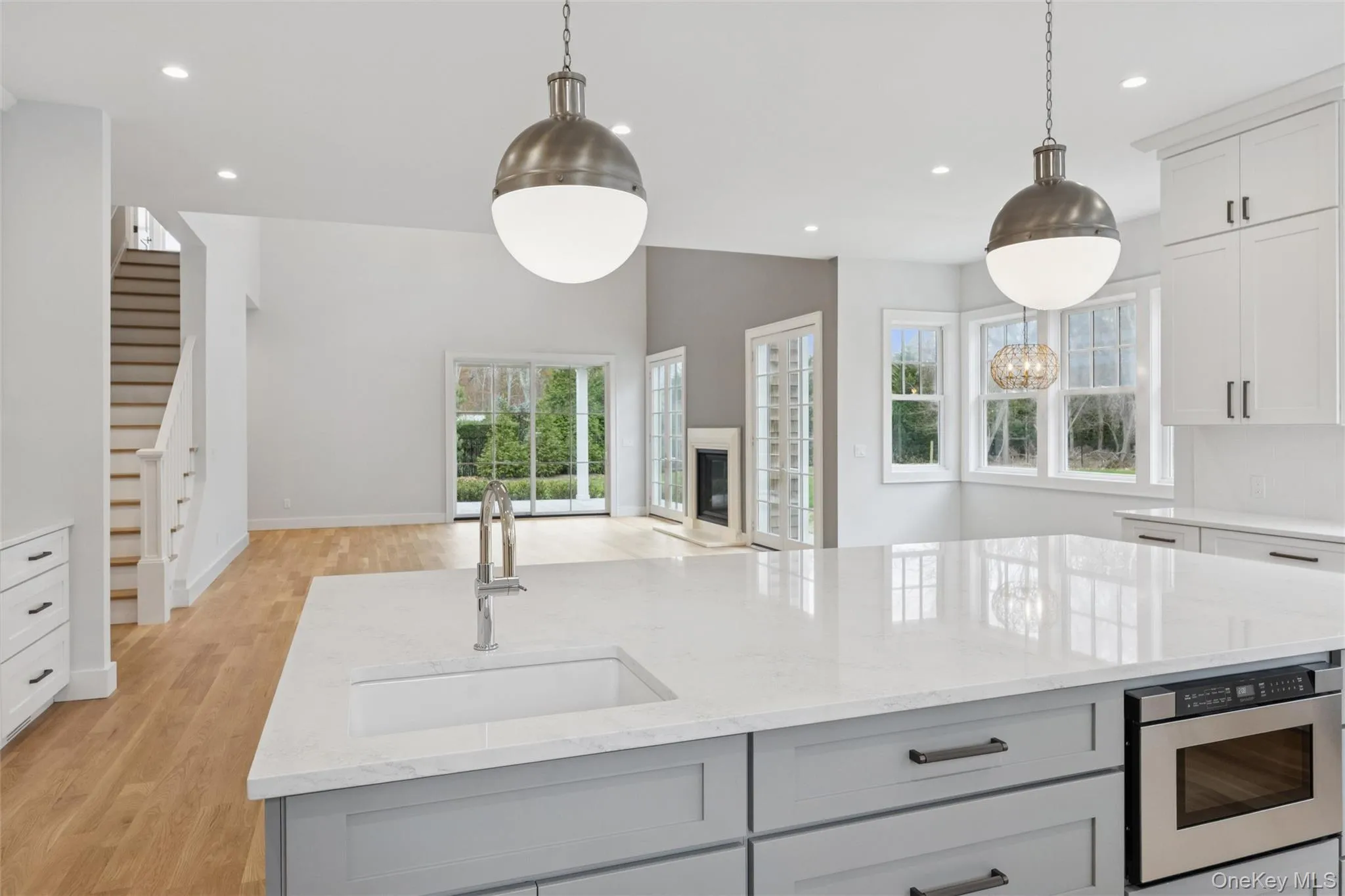 Kitchen featuring gray cabinetry, light stone countertops, hanging light fixtures, and recessed lighting Kitchen featuring gray cabinetry, light stone countertops, hanging light fixtures, and recessed lighting