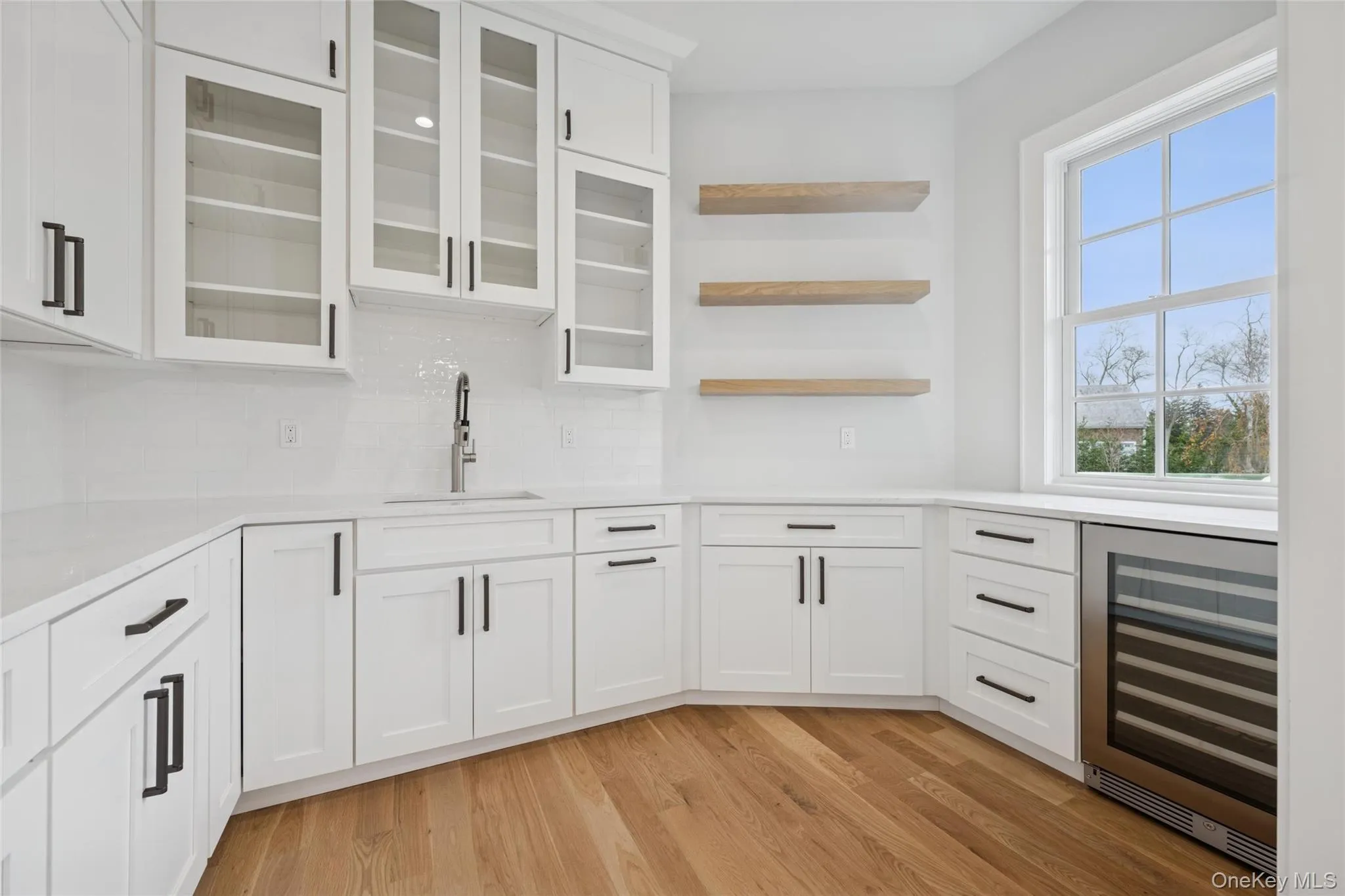 Butler's Pantry featuring open shelves, white cabinets, wine cooler, and light stone counters Butler's Pantry featuring open shelves, white cabinets, wine cooler, and light stone counters
