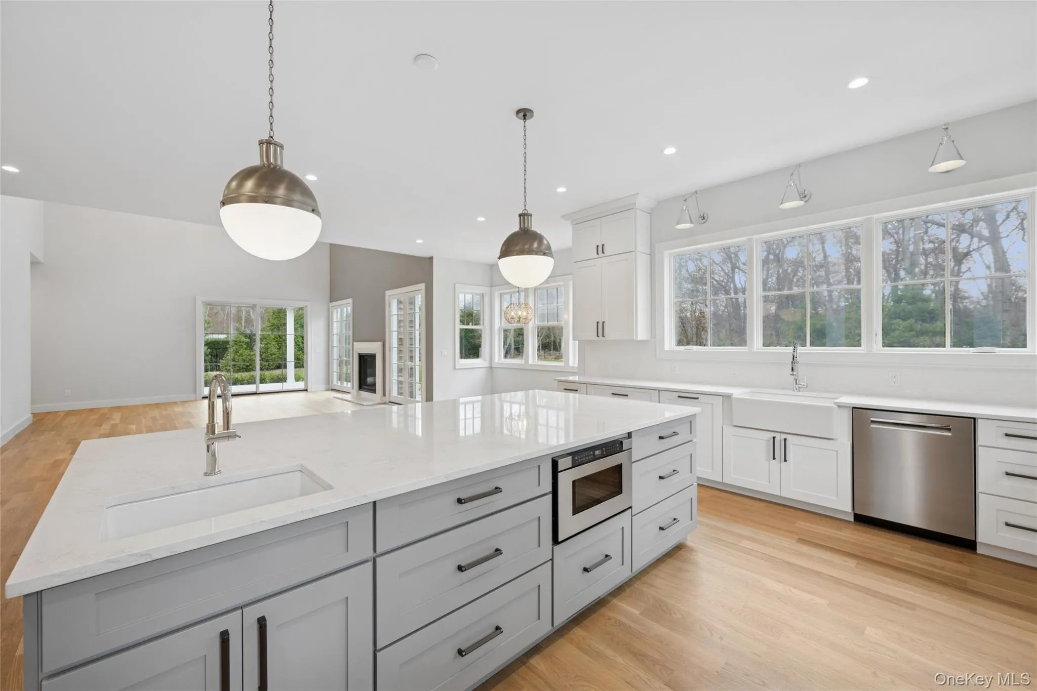 Kitchen featuring light wood finished floors, gray cabinetry, stainless steel appliances, white cabinetry, and light stone counters Kitchen featuring light wood finished floors, gray cabinetry, stainless steel appliances, white cabinetry, and light stone counters