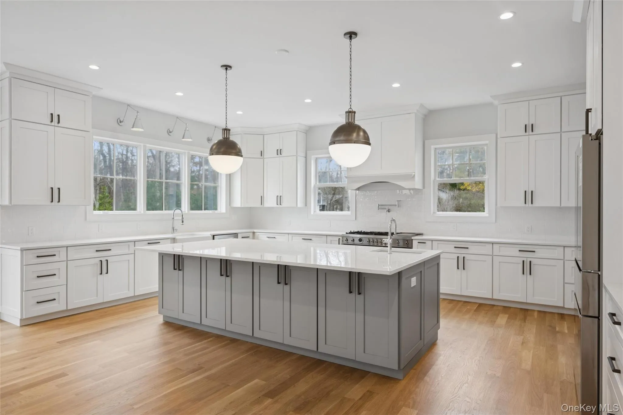 Kitchen with gray cabinets, a kitchen island with sink, white cabinetry, and recessed lighting Kitchen with gray cabinets, a kitchen island with sink, white cabinetry, and recessed lighting