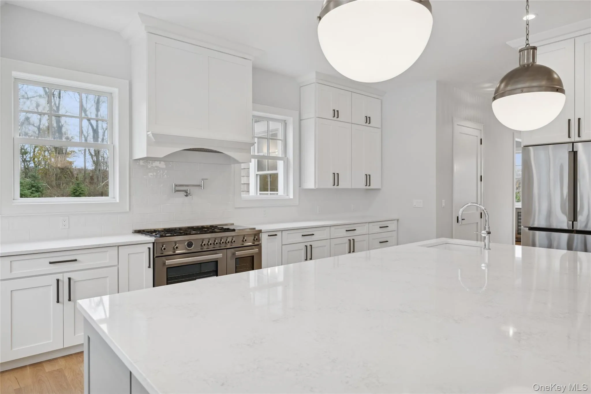 Kitchen with stainless steel appliances, light stone countertops, white cabinetry, tasteful backsplash, and light wood-type flooring Kitchen with stainless steel appliances, light stone countertops, white cabinetry, tasteful backsplash, and light wood-type flooring