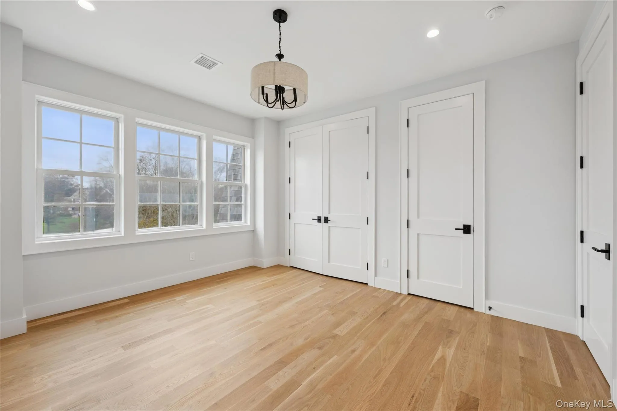 Bedroom with multiple closets, light wood-style flooring, and recessed lighting Bedroom with multiple closets, light wood-style flooring, and recessed lighting