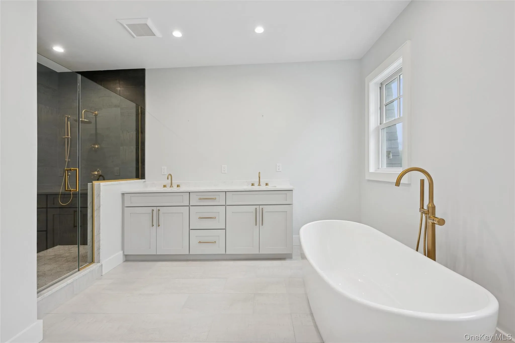 Primary bathroom with double vanity, a freestanding bath, a stall shower, recessed lighting, and light tile patterned flooring Primary bathroom with double vanity, a freestanding bath, a stall shower, recessed lighting, and light tile patterned flooring