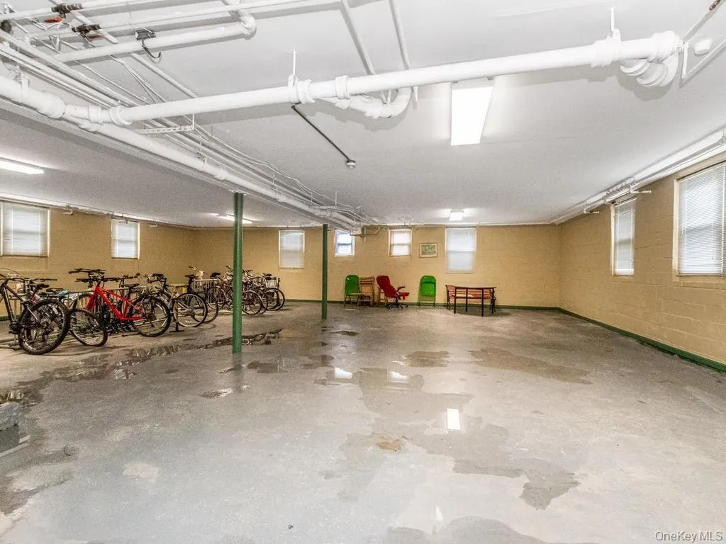 Expansive utility space with visible ceiling piping, a concrete floor, and multiple windows Expansive utility space with visible ceiling piping, a concrete floor, and multiple windows