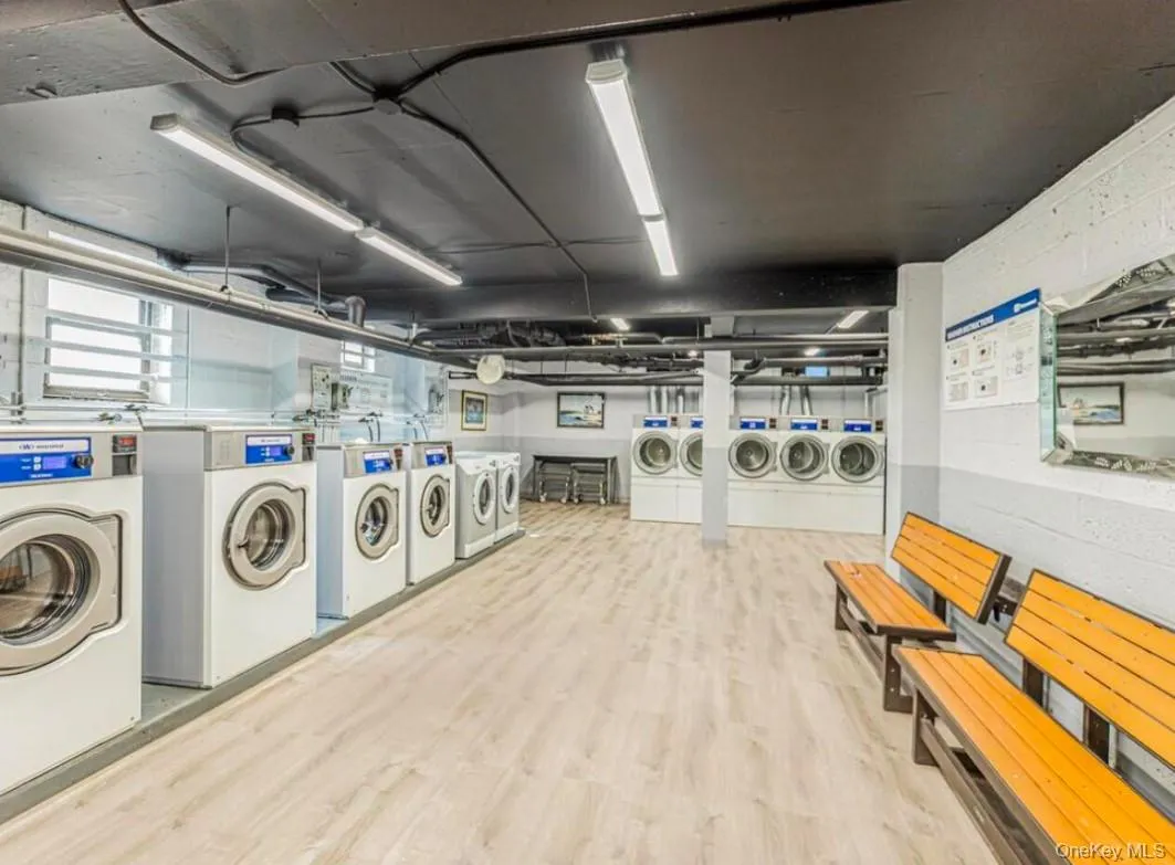 Communal laundry room featuring washer and clothes dryer and wood finished floors Communal laundry room featuring washer and clothes dryer and wood finished floors