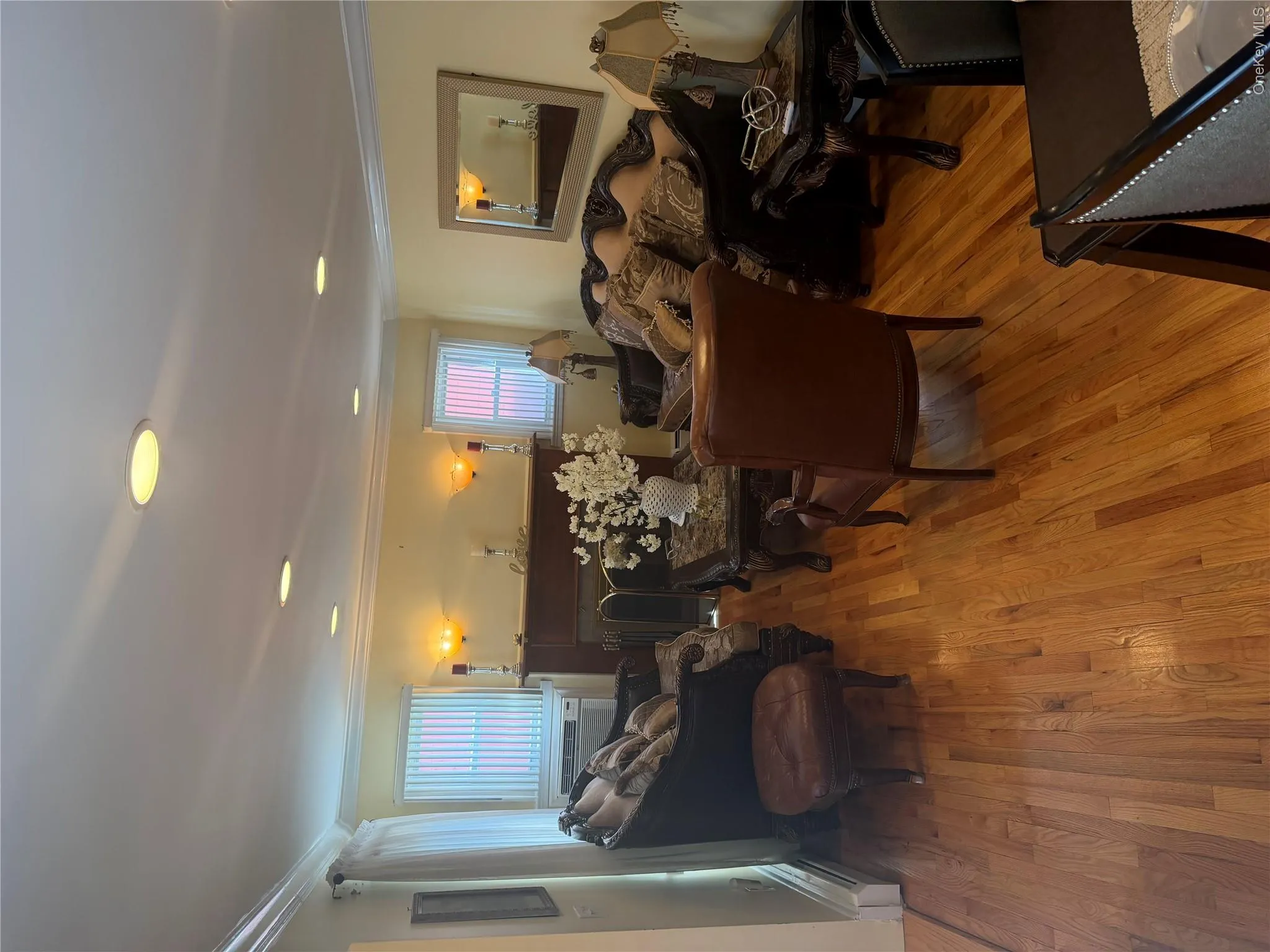 Living space featuring wood-finish flooring, recessed lighting, and a prominent fireplace with a dark wood mantel Living space featuring wood-finish flooring, recessed lighting, and a prominent fireplace with a dark wood mantel