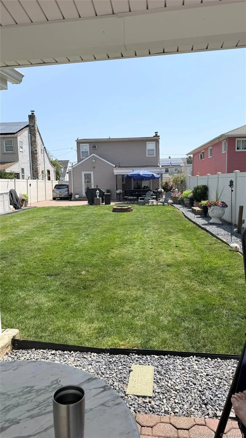Expansive green lawn with a gravel border and integrated fire pit Expansive green lawn with a gravel border and integrated fire pit