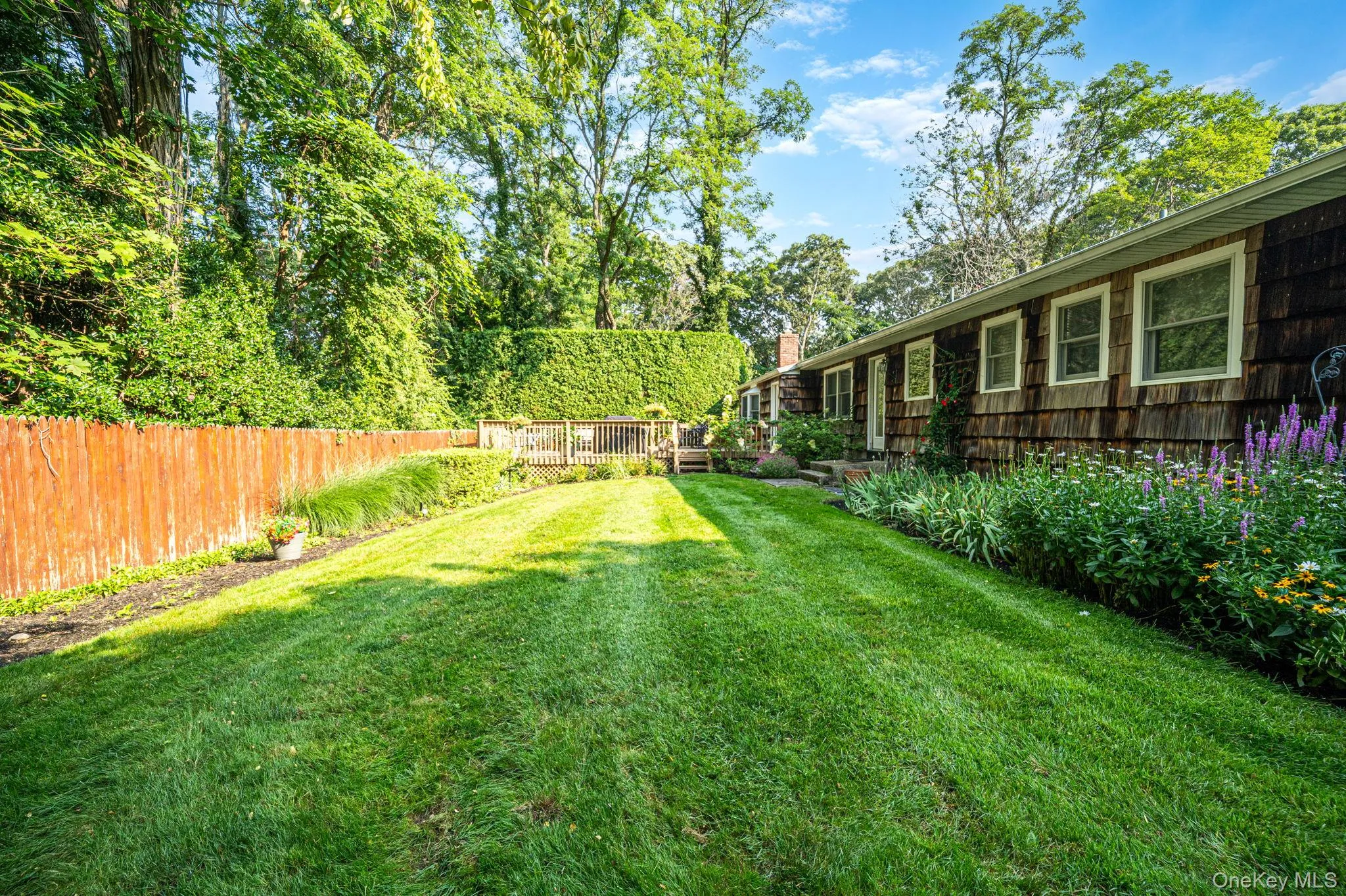 Expansive lawn with natural wood fencing, a dedicated garden area, and a large wood deck Expansive lawn with natural wood fencing, a dedicated garden area, and a large wood deck