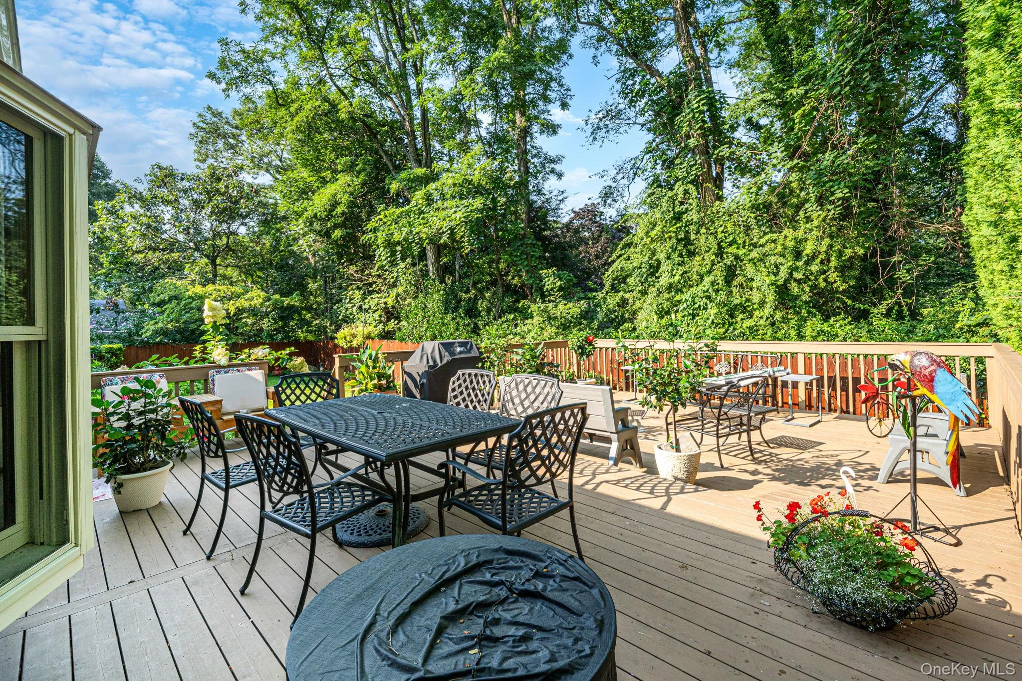 Spacious wood-finish deck with a wood railing and ample green landscaping Spacious wood-finish deck with a wood railing and ample green landscaping