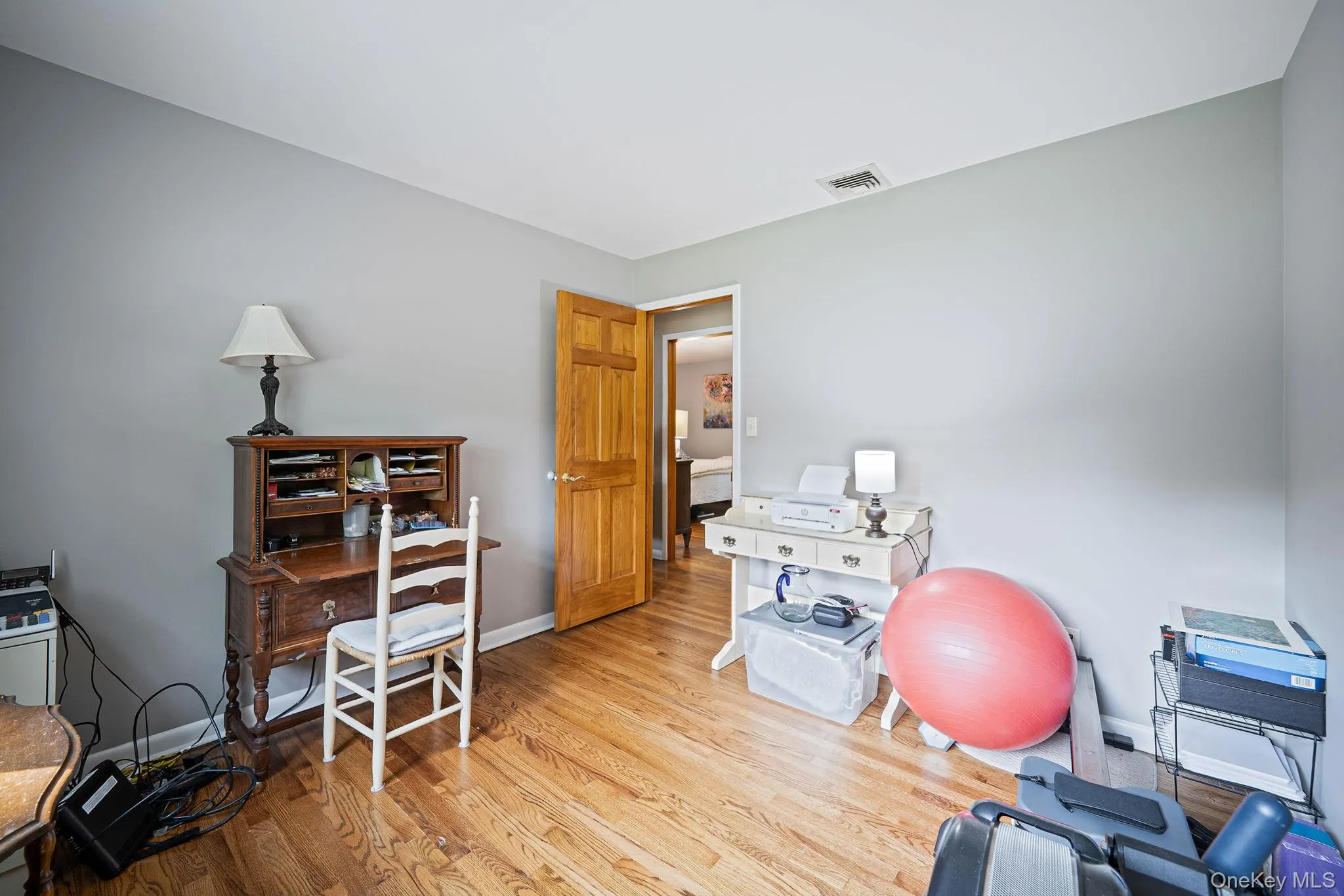 Hardwood flooring throughout, light gray wall paint, and a solid wood paneled door Hardwood flooring throughout, light gray wall paint, and a solid wood paneled door