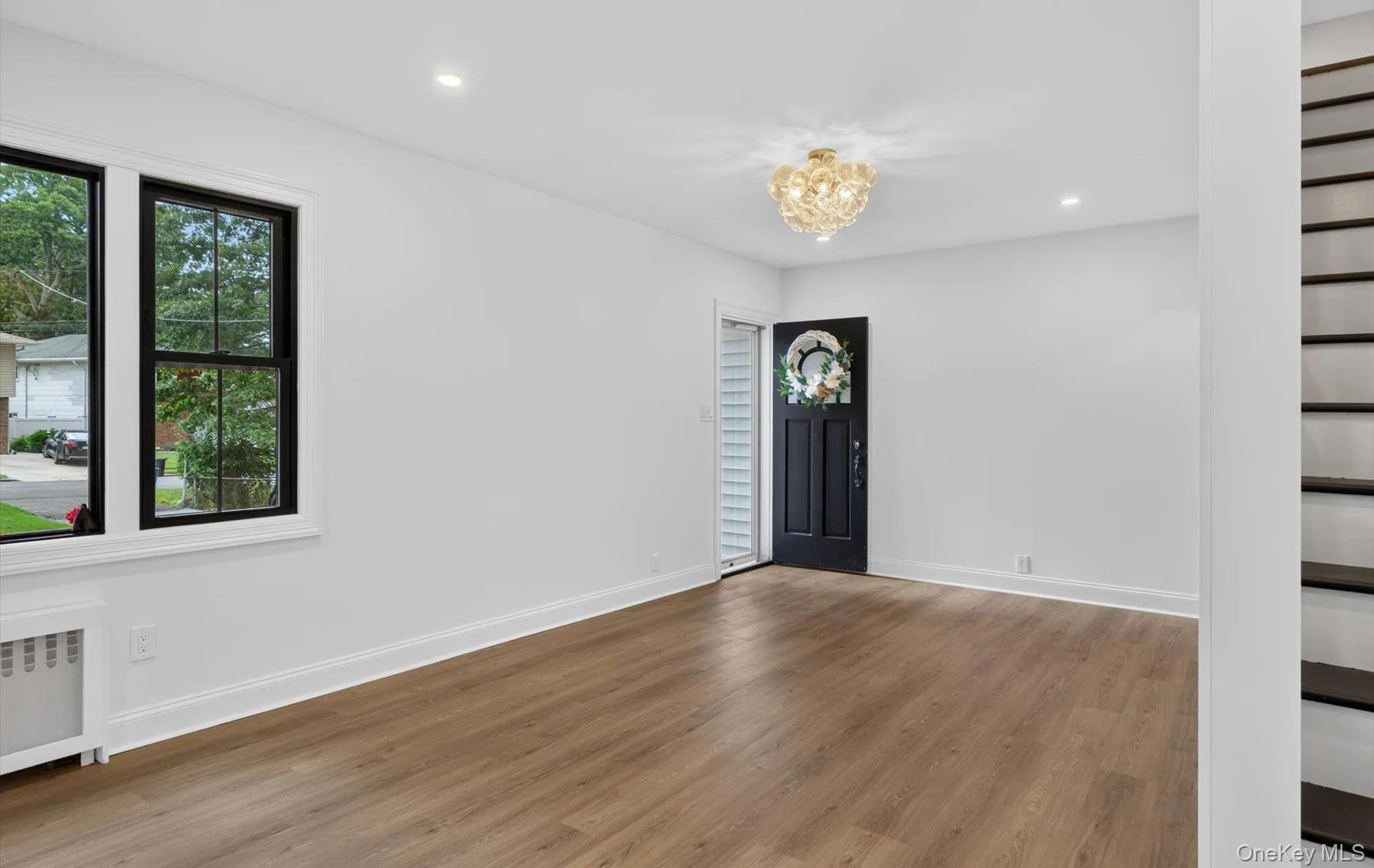 Open living area featuring wood-finish flooring, recessed lighting, and a contemporary chandelier Open living area featuring wood-finish flooring, recessed lighting, and a contemporary chandelier
