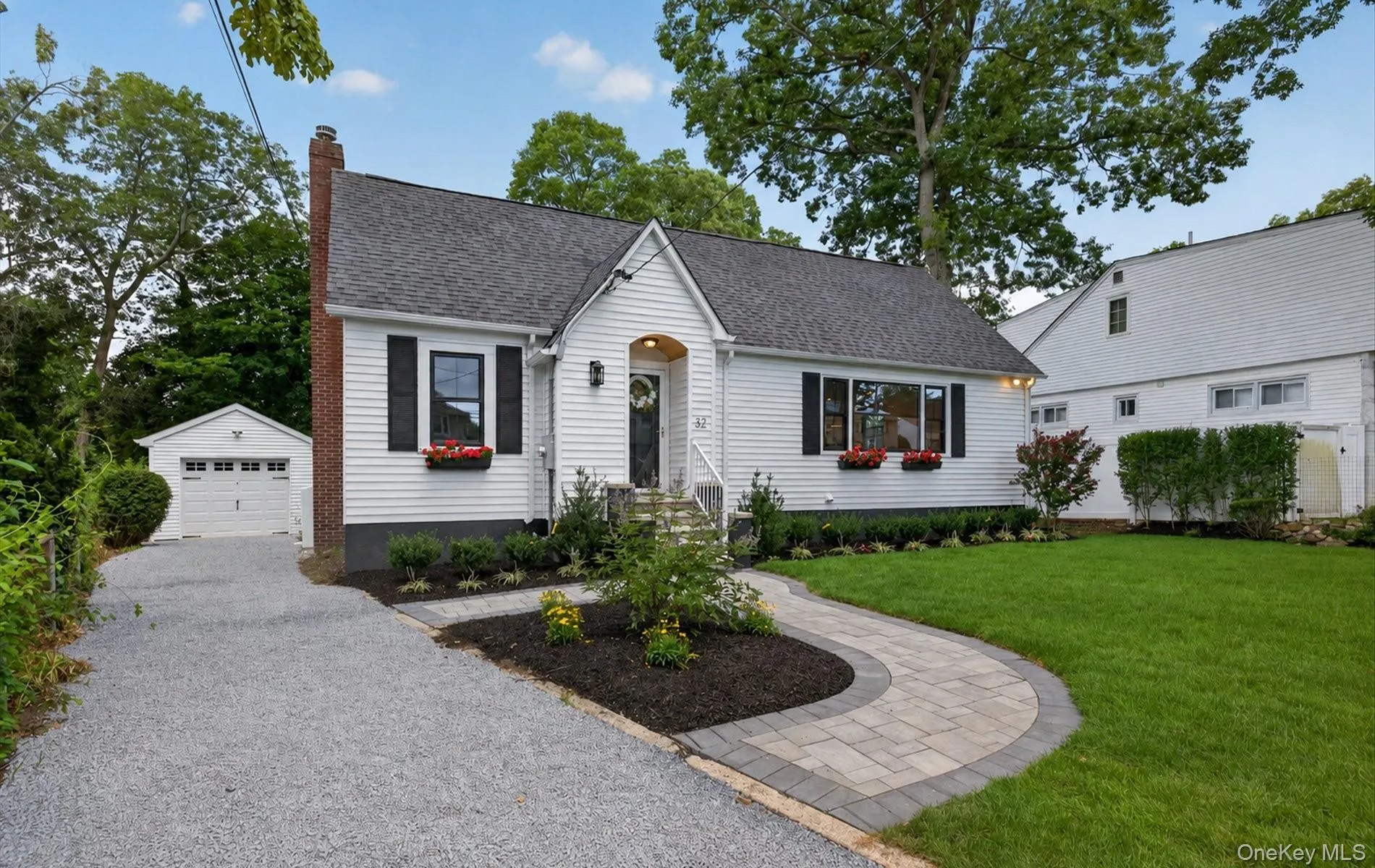 Charming white siding residence featuring a dark shingle roof and a prominent brick chimney Charming white siding residence featuring a dark shingle roof and a prominent brick chimney