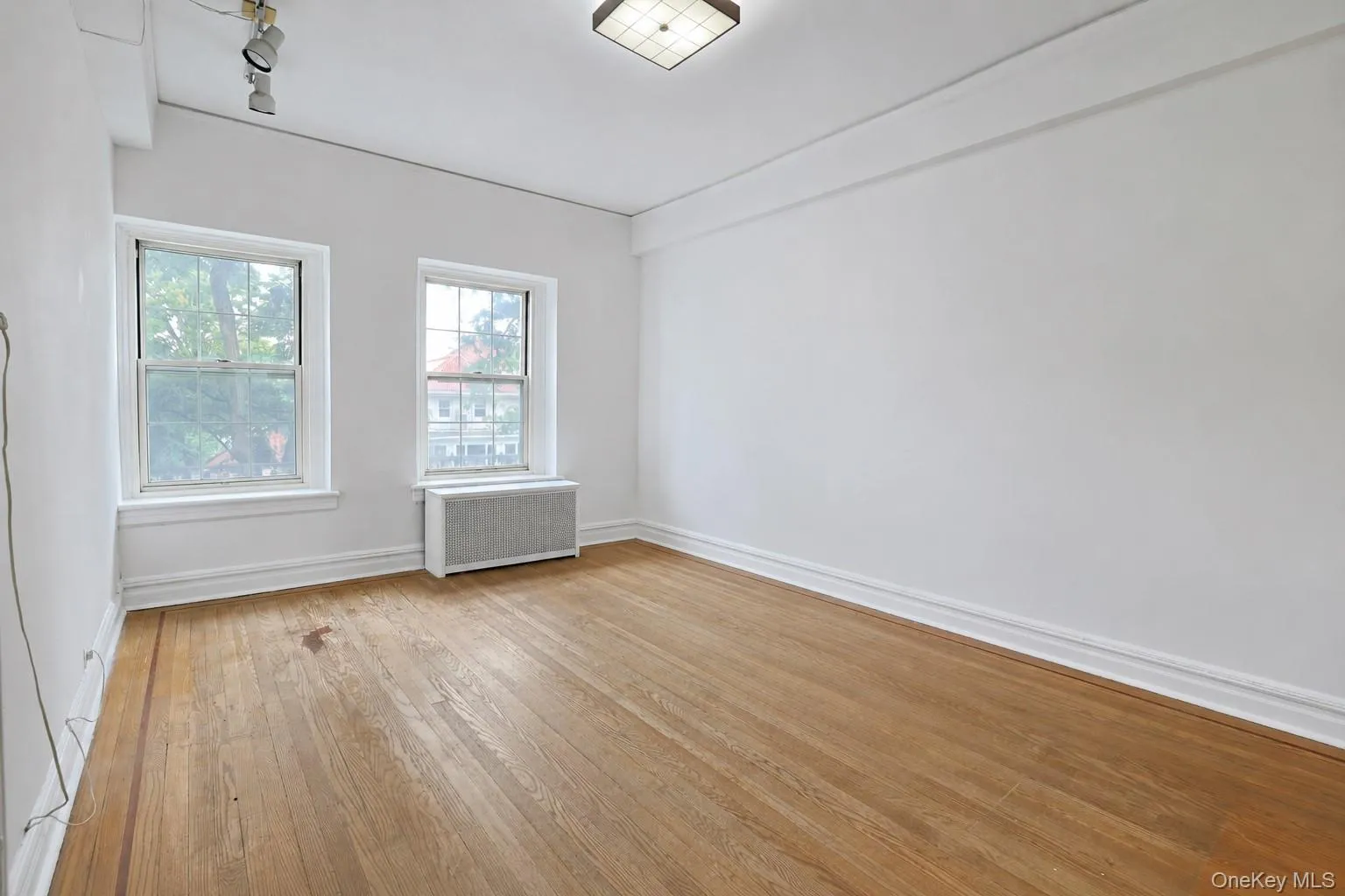 Generously sized bedroom with hardwood floors, multiple windows, and abundant natural light. Generously sized bedroom with hardwood floors, multiple windows, and abundant natural light.
