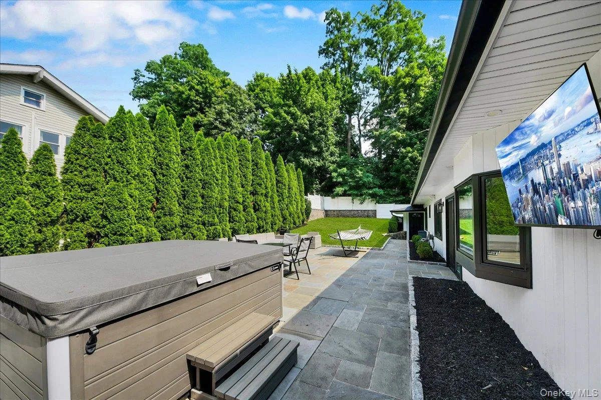 Backyard with stone patio and tv - completely fenced in & lined with privacy trees Backyard with stone patio and tv - completely fenced in & lined with privacy trees