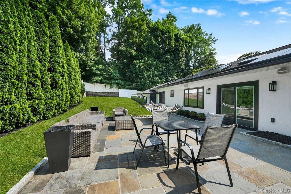 Backyard with stone patio and tv - completely fenced in & lined with privacy trees Backyard with stone patio and tv - completely fenced in & lined with privacy trees