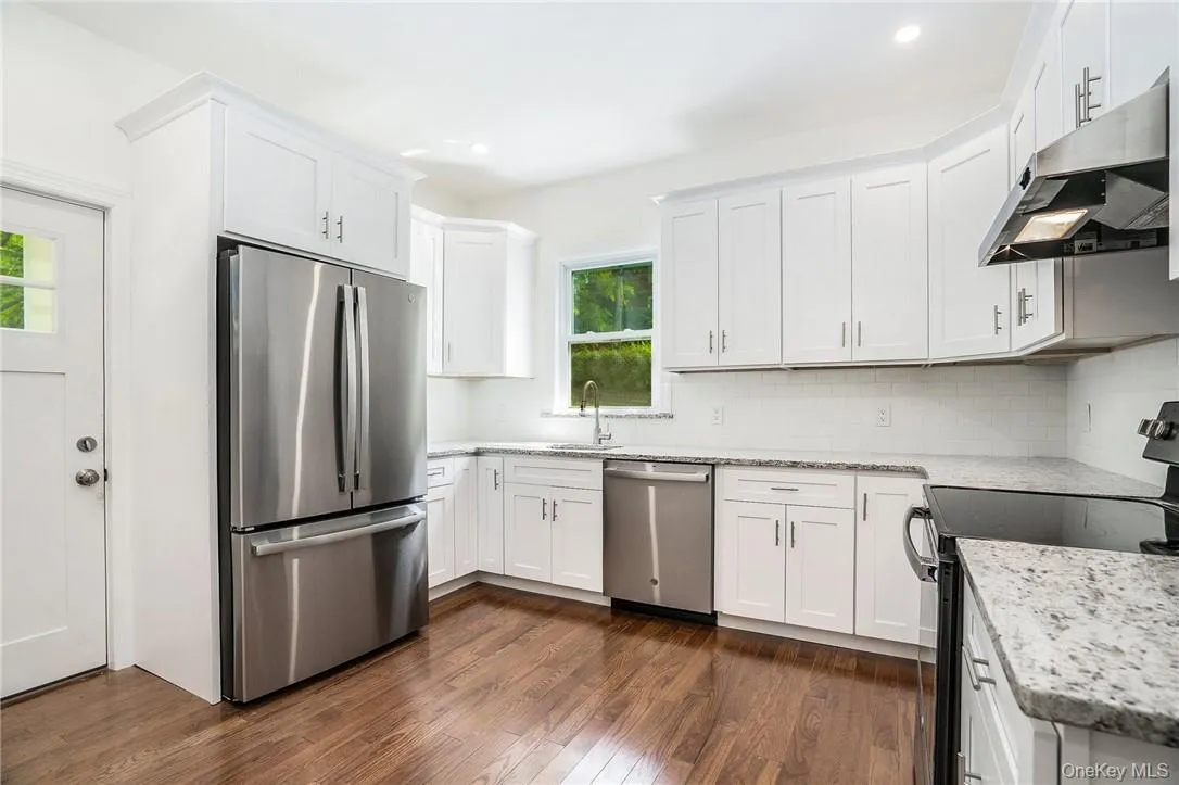 Kitchen featuring dark hardwood / wood-style floors, plenty of natural light, stainless steel appliances, and backsplash Kitchen featuring dark hardwood / wood-style floors, plenty of natural light, stainless steel appliances, and backsplash