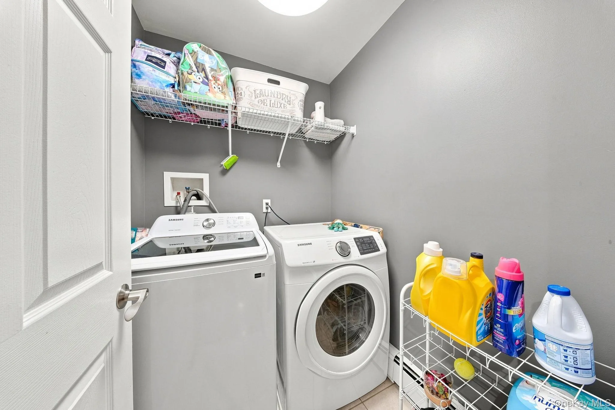 Laundry area featuring light gray walls, a white door, and overhead wire shelving Laundry area featuring light gray walls, a white door, and overhead wire shelving