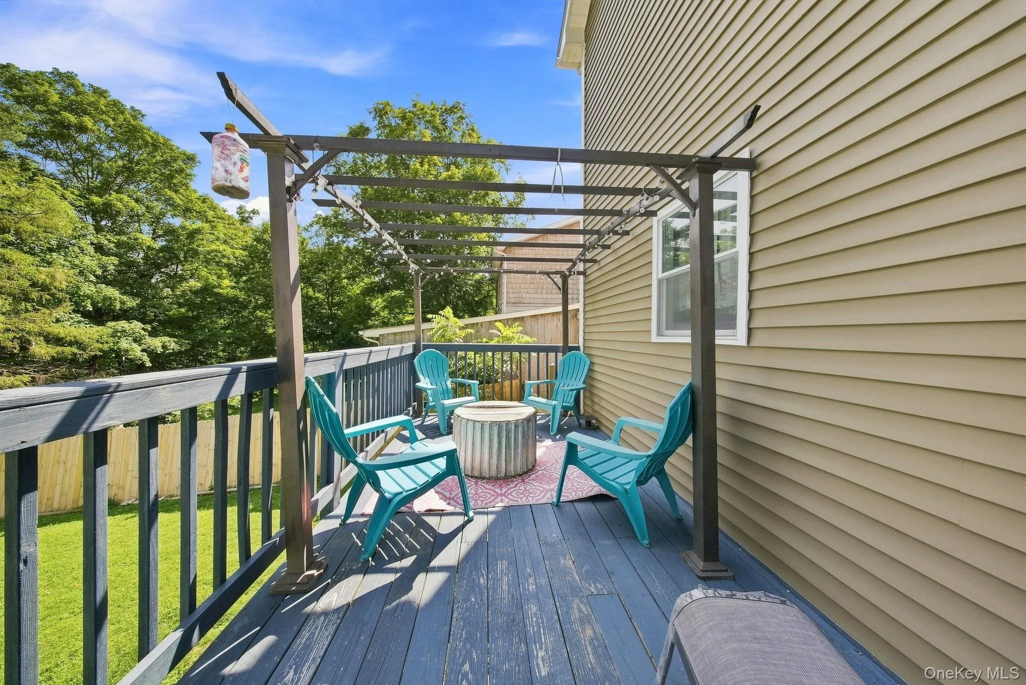 Spacious composite deck featuring a wood-finish surface, black metal railing, and attached pergola with integrated overhead lighting Spacious composite deck featuring a wood-finish surface, black metal railing, and attached pergola with integrated overhead lighting