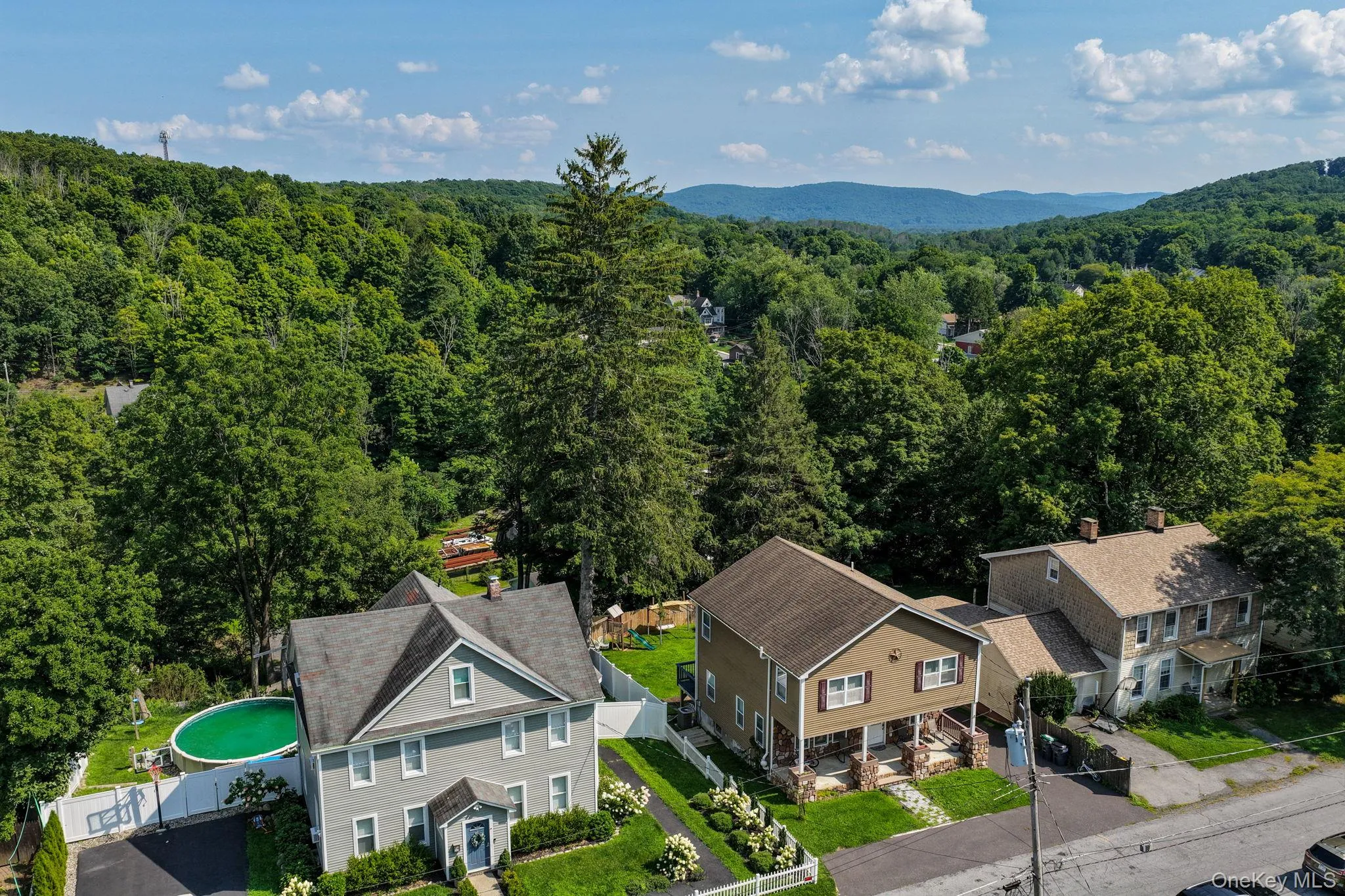 Scenic aerial perspective showcasing three residential properties nestled within mature landscaping and tree-lined surroundings Scenic aerial perspective showcasing three residential properties nestled within mature landscaping and tree-lined surroundings