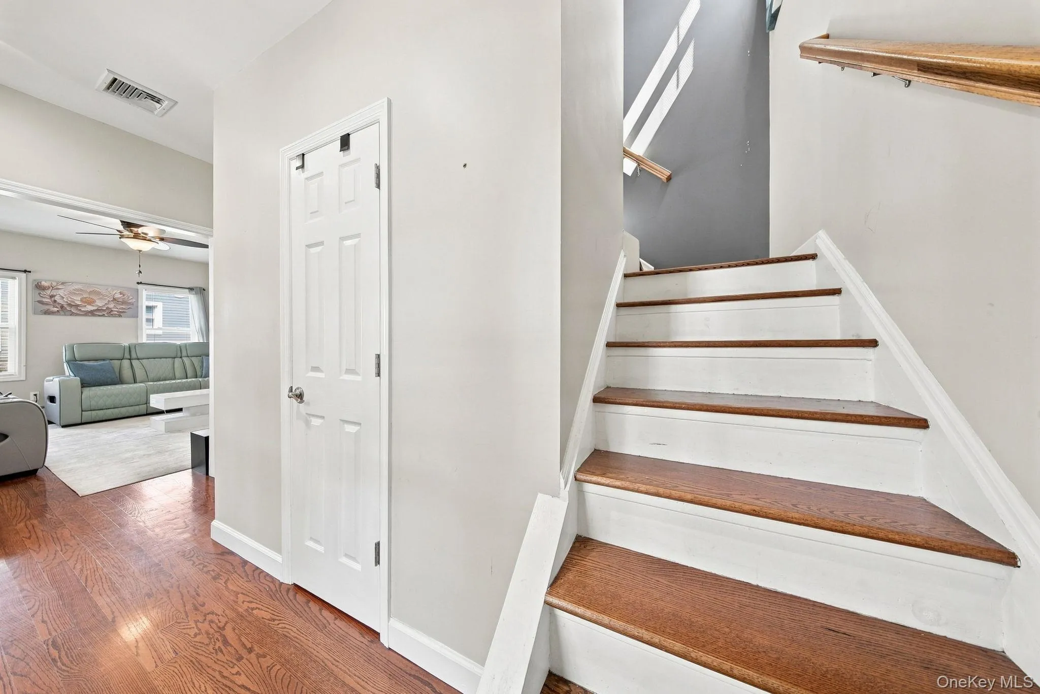 Bright staircase with wood-finish treads and white risers, accented by a natural wood handrail and skylight above Bright staircase with wood-finish treads and white risers, accented by a natural wood handrail and skylight above