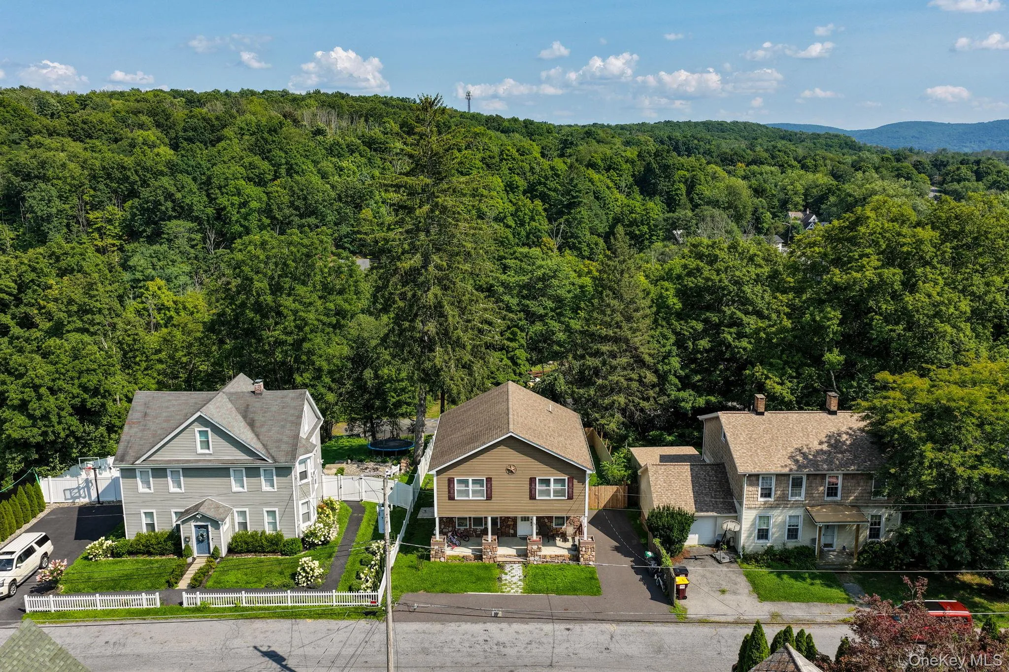 Two-story residence with a front porch, white picket fence, and established landscaping Two-story residence with a front porch, white picket fence, and established landscaping
