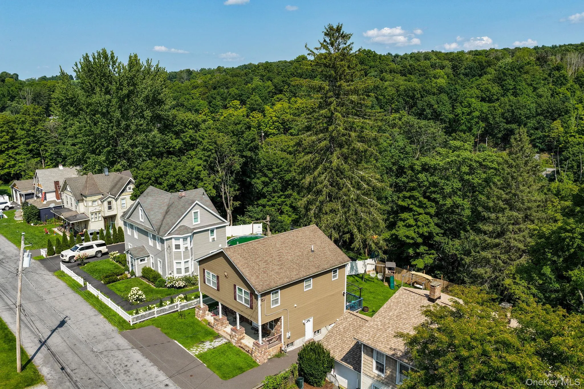 Brick Colonial situated on expansive wooded grounds featuring a multi-level design with elevated deck, attached garage, and mature landscaping with established trees providing privacy and natural screening Brick Colonial situated on expansive wooded grounds featuring a multi-level design with elevated deck, attached garage, and mature landscaping with established trees providing privacy and natural screening