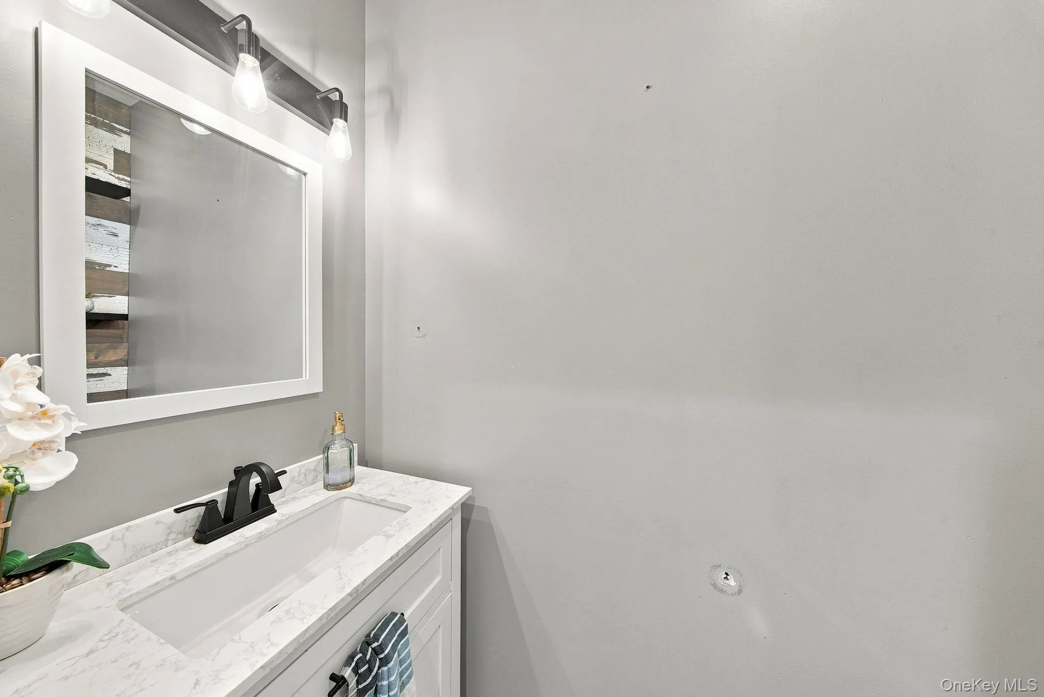 Modern half bathroom vanity featuring a white marble-finish countertop, integrated sink basin, and matte black faucet Modern half bathroom vanity featuring a white marble-finish countertop, integrated sink basin, and matte black faucet