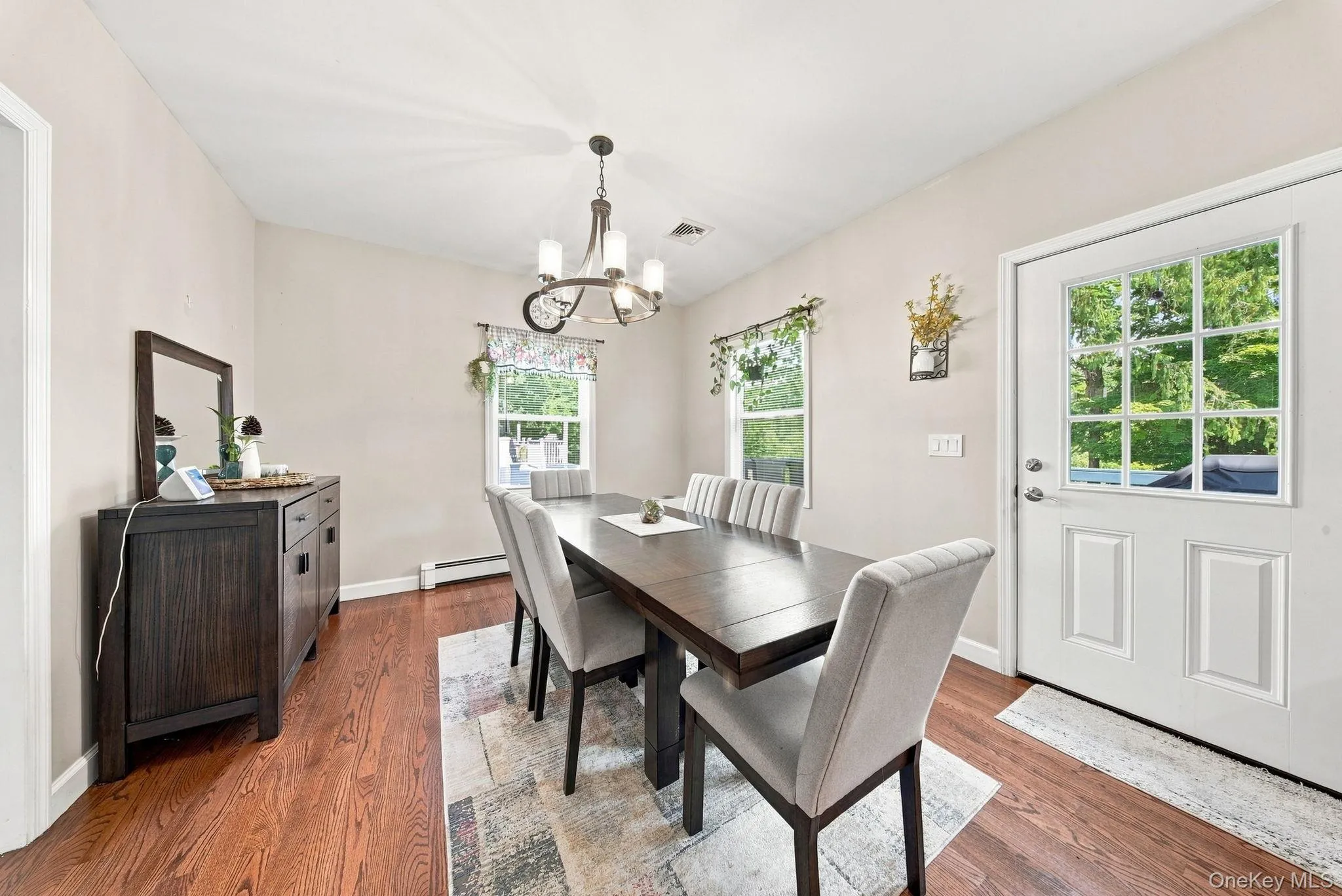 Bright dining space featuring hardwood flooring, a dark wood dining table with upholstered chairs, and abundant natural light from multiple multi-pane windows and glass doors Bright dining space featuring hardwood flooring, a dark wood dining table with upholstered chairs, and abundant natural light from multiple multi-pane windows and glass doors