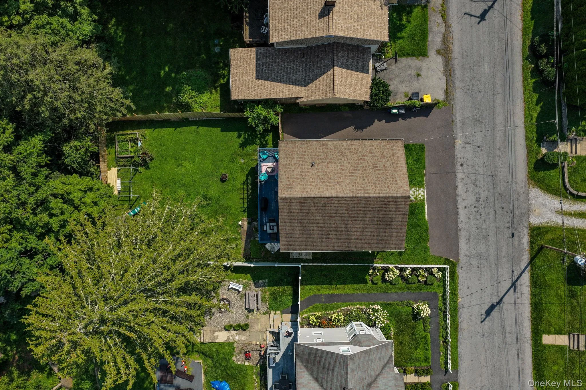 Aerial view showcasing a residential lot with mature landscaping, manicured lawn, multi-car driveway, and a two-story home featuring dimensional asphalt shingle roofing Aerial view showcasing a residential lot with mature landscaping, manicured lawn, multi-car driveway, and a two-story home featuring dimensional asphalt shingle roofing