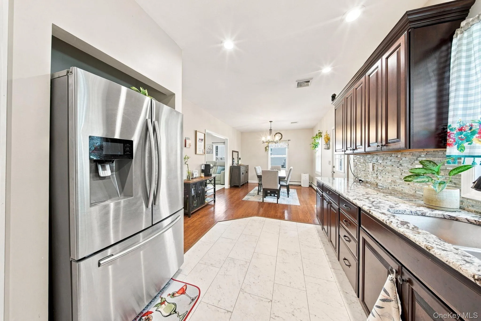 Kitchen featuring dark wood cabinetry, light stone countertops, a mosaic tile backsplash, and recessed lighting Kitchen featuring dark wood cabinetry, light stone countertops, a mosaic tile backsplash, and recessed lighting