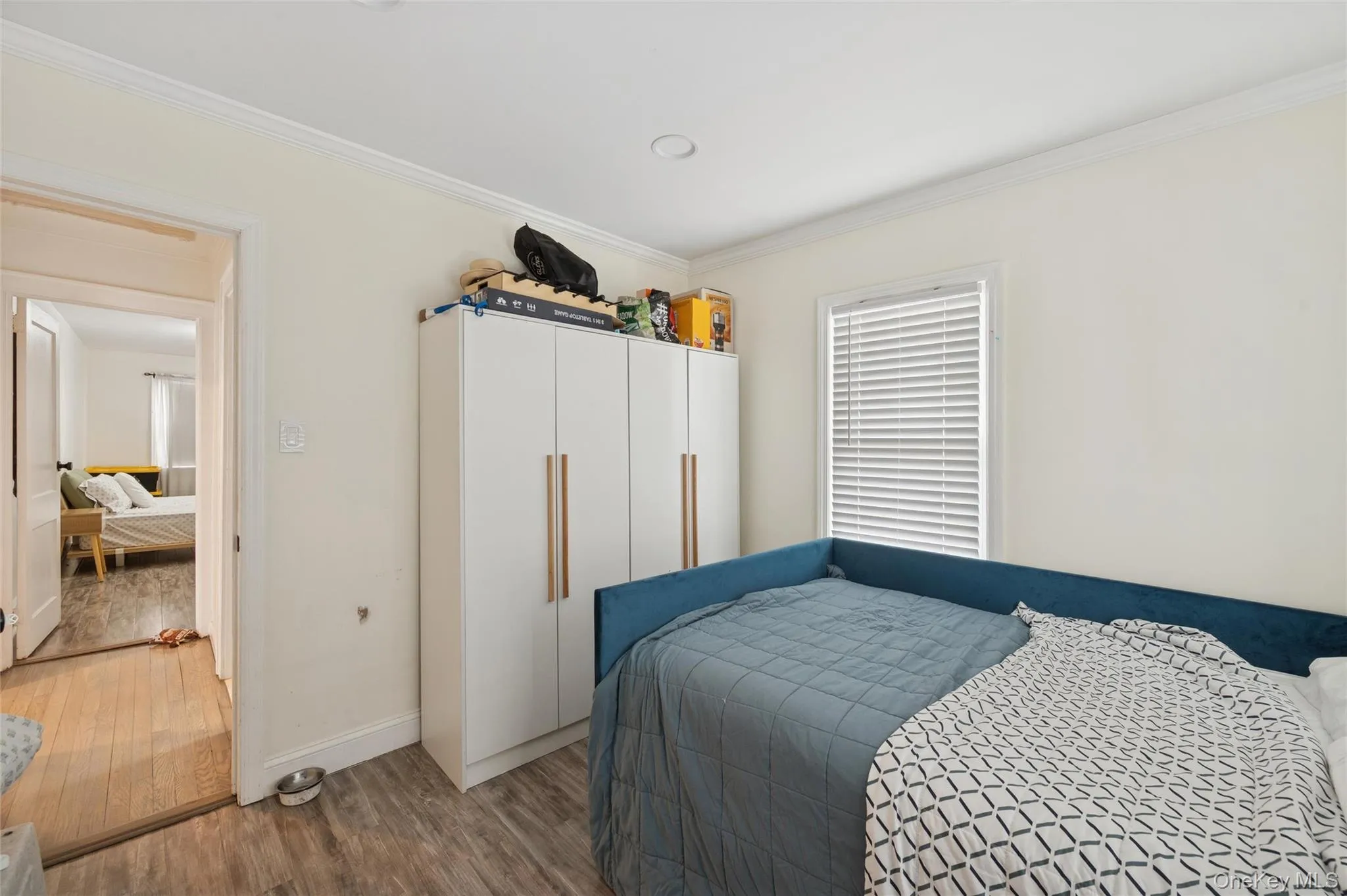 Bedroom featuring wood finished floors and ornamental molding Bedroom featuring wood finished floors and ornamental molding